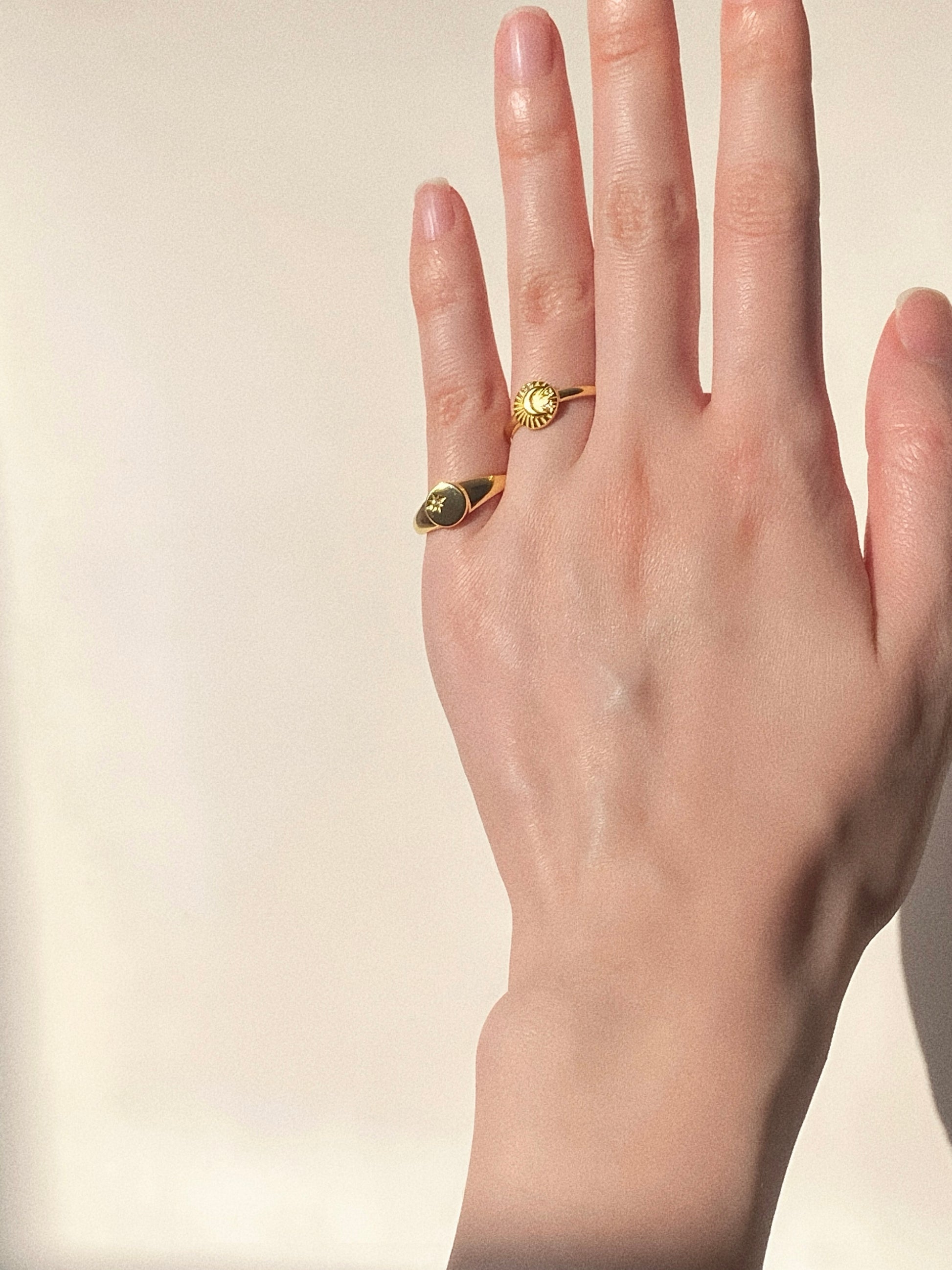 Lifestyle shot showing the gold celestial ring paired with a minimalist signet ring for a trendy stack.