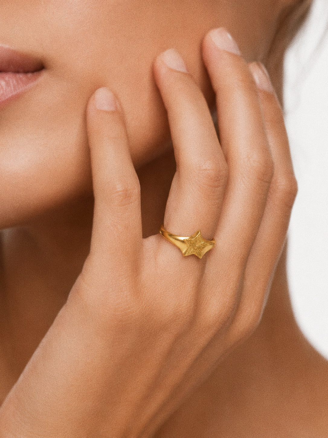 Nova star signet ring in 18k gold plated silver worn on the hand, engraved star face catching the light.