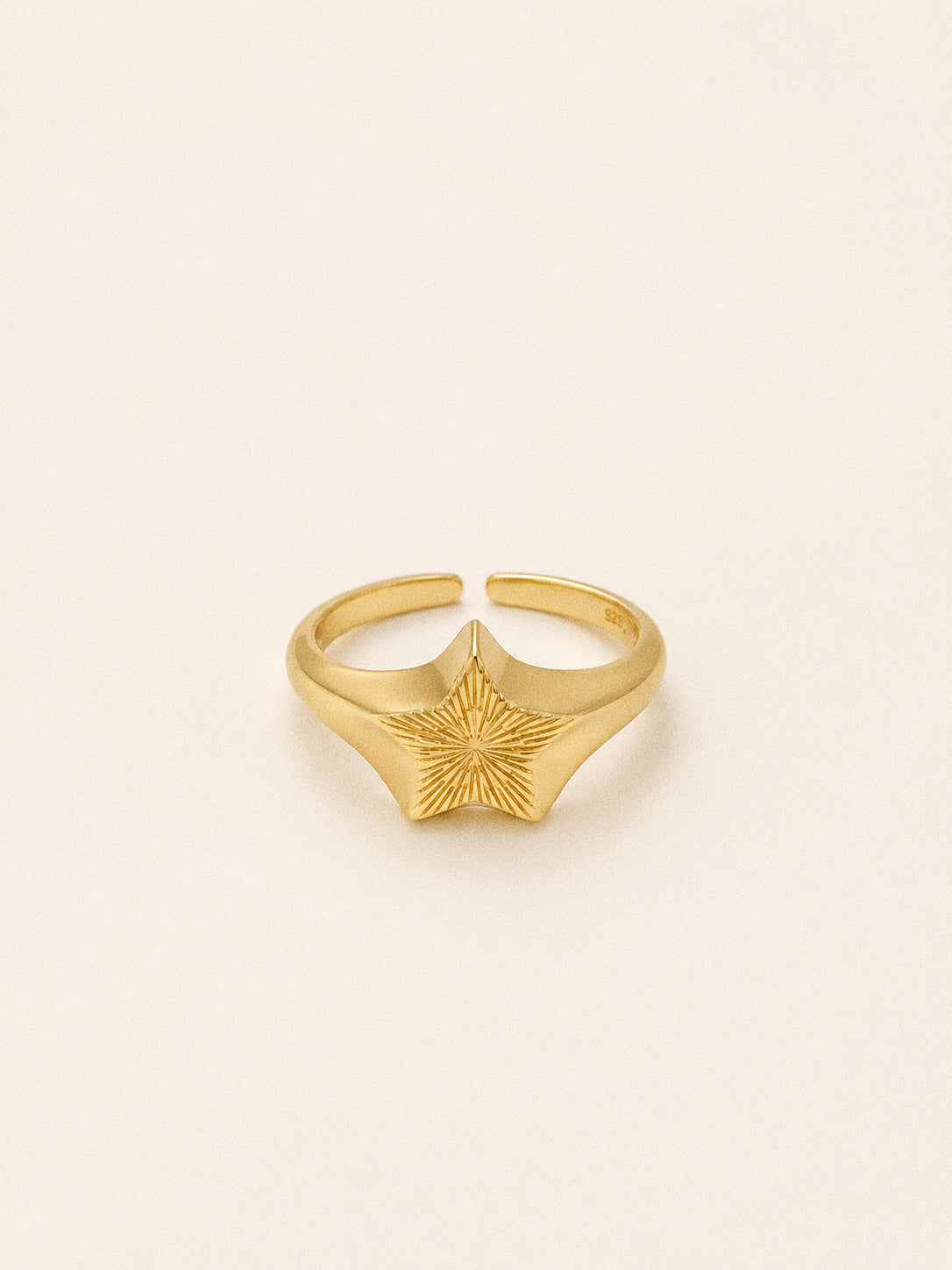 Gold plated star signet ring seen from above, sunburst rays radiating from the centre of the five pointed star.