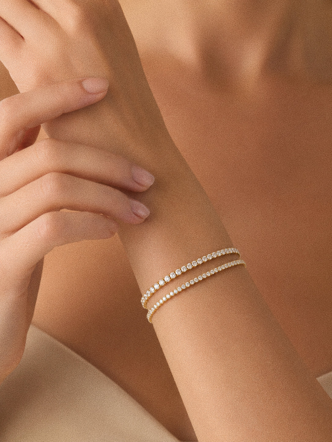 Two gold cubic zirconia tennis bracelets stacked and layered on a model's wrist, waterproof everyday jewellery