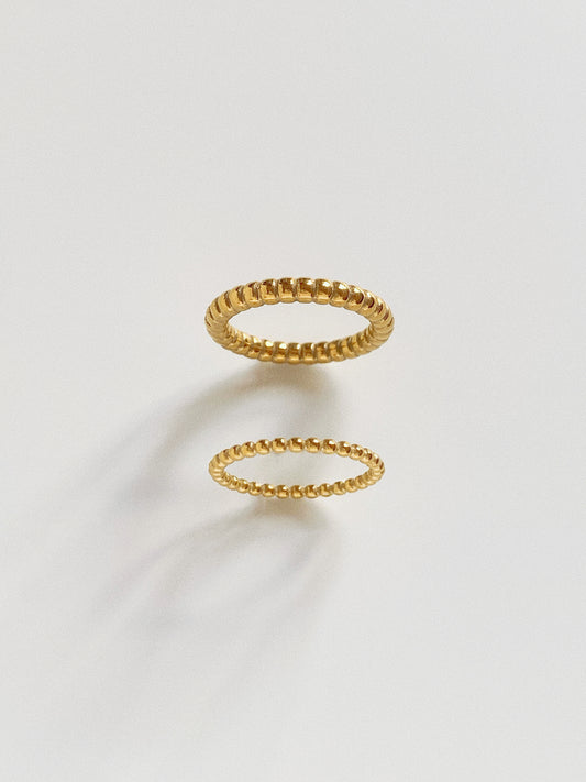 Comparison view of wide and narrow gold beaded rings in 18k gold plated titanium.