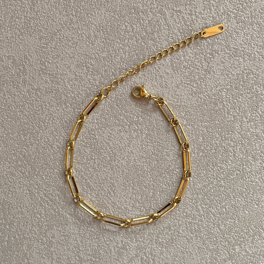 Flat-lay of adjustable gold paperclip bracelet with extender chain and clasp, tarnish-resistant stainless steel