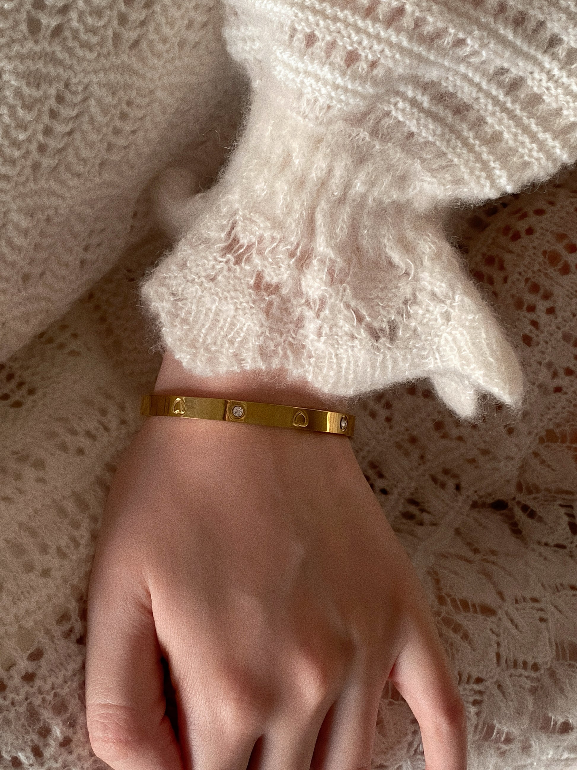 Isolated view of gold oval hinge bangle showing the 0.6cm width and crystal heart details.