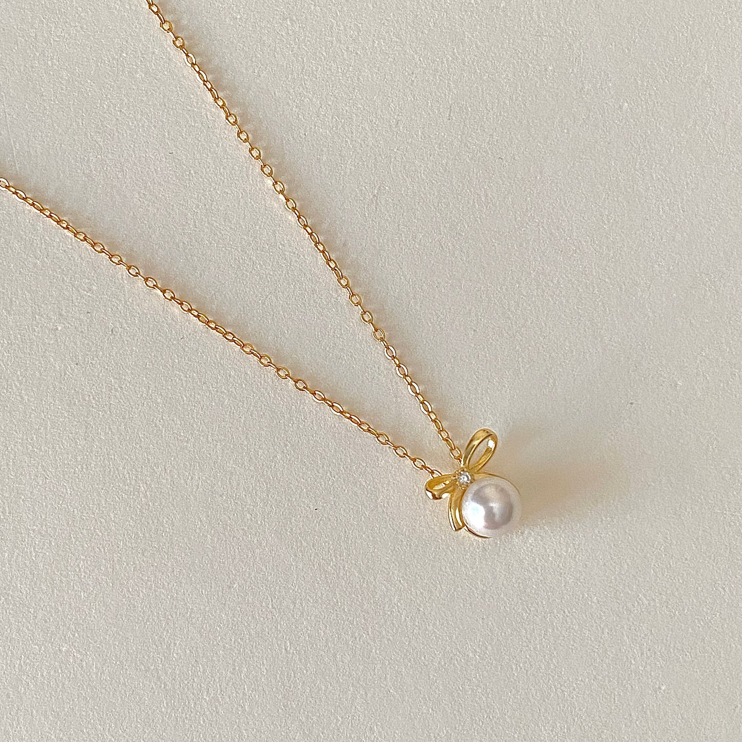 Gold bow pearl pendant necklace close-up, 6 mm pearl on 18k gold-plated 925 chain