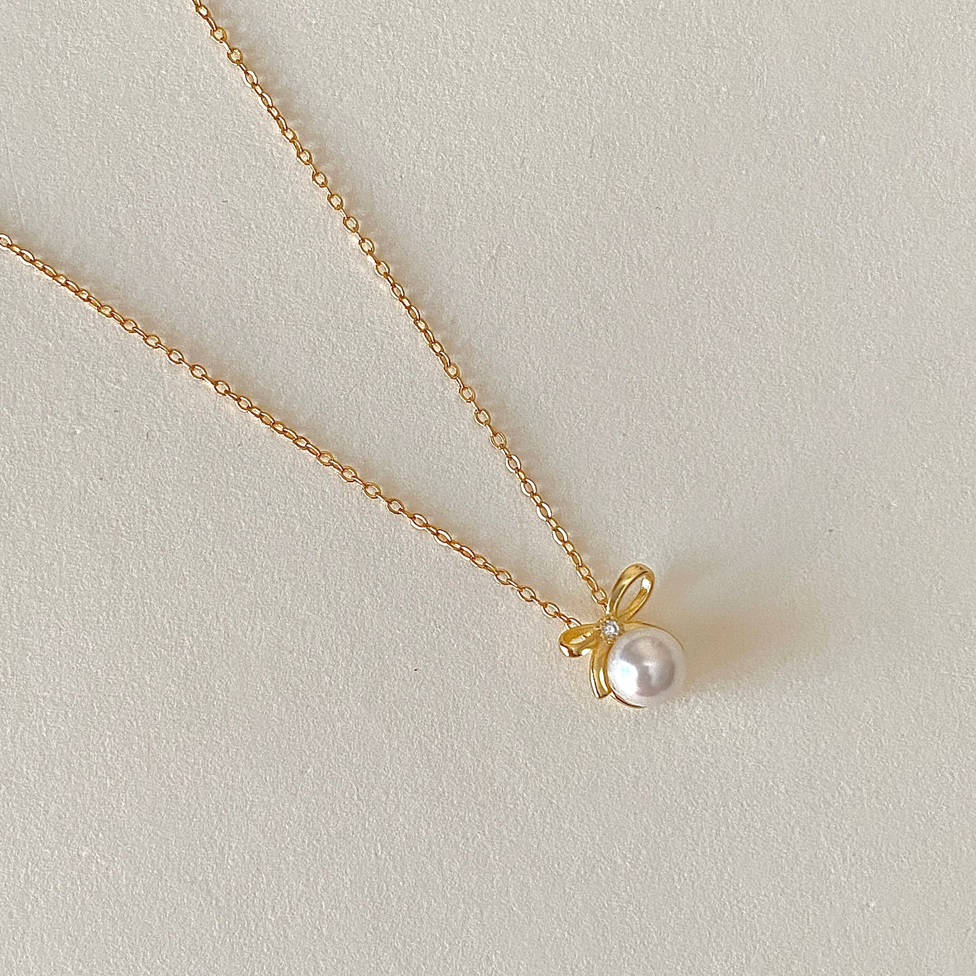 Gold bow pearl pendant necklace close-up, 6 mm pearl on 18k gold-plated 925 chain