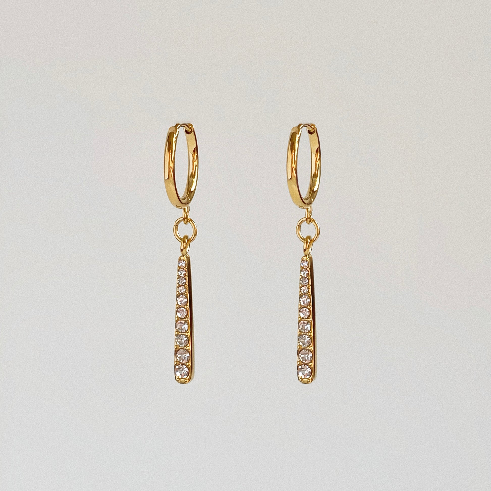 Waterproof gold huggie earrings with a dangling 2.3cm pave crystal bar pendant.