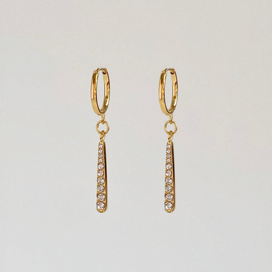 Waterproof gold huggie earrings with a dangling 2.3cm pave crystal bar pendant.