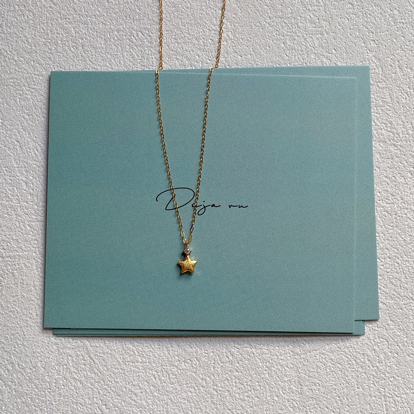Tiny gold star pendant necklace on teal Deja vu Jewellery card
