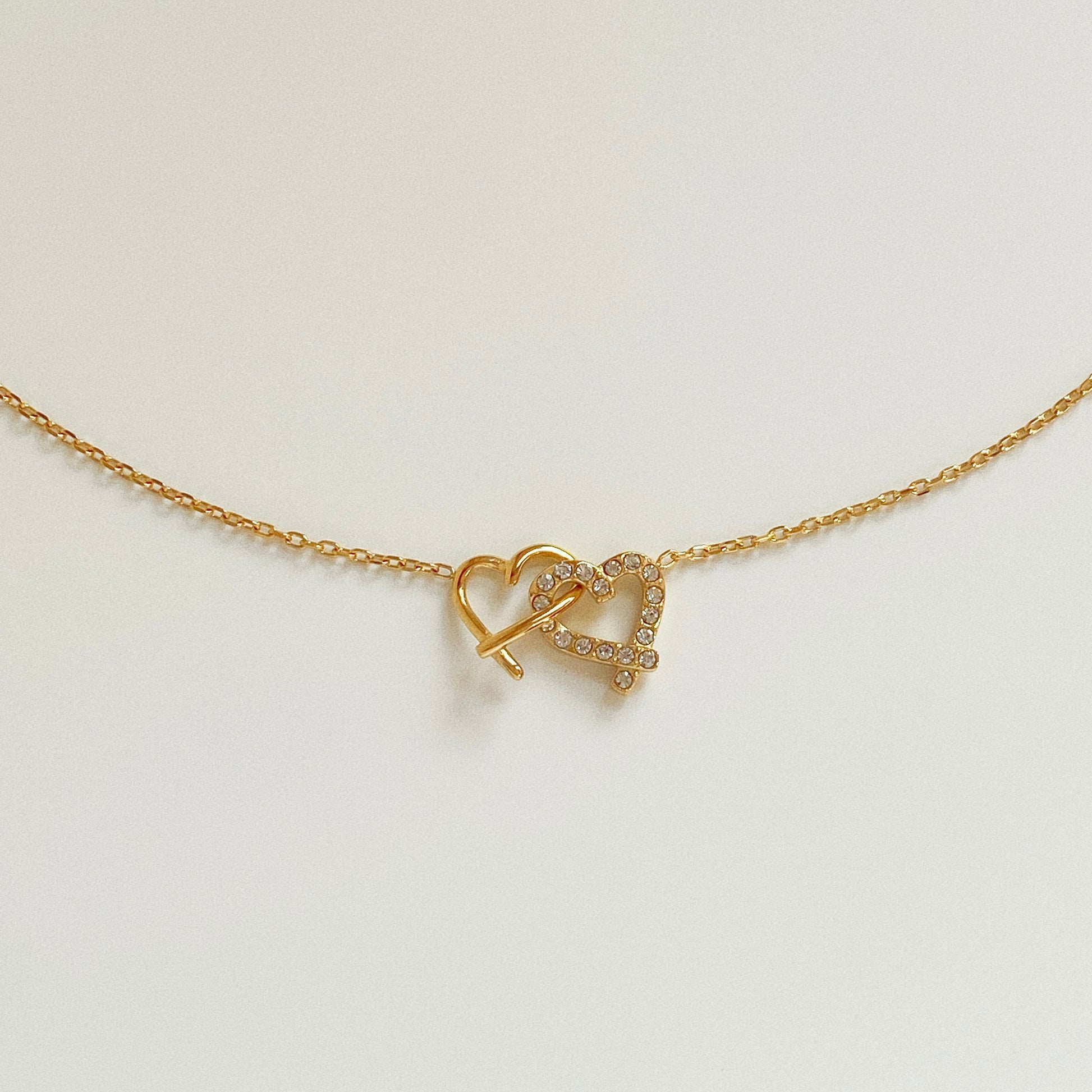 Waterproof gold heart necklace flat lay, stainless steel jewelry isolated on white background.