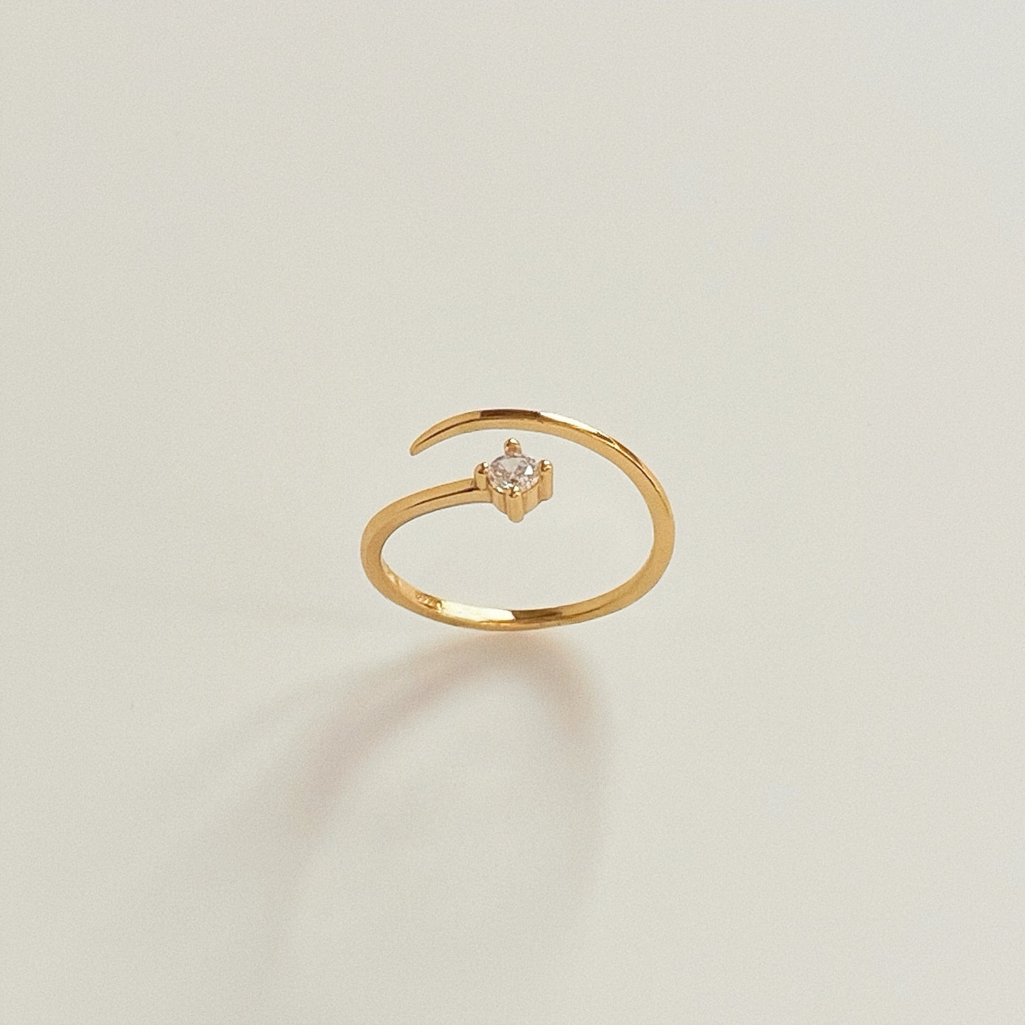 Solo Spark adjustable gold pinky ring standing upright with single cubic zirconia facing forward on light background