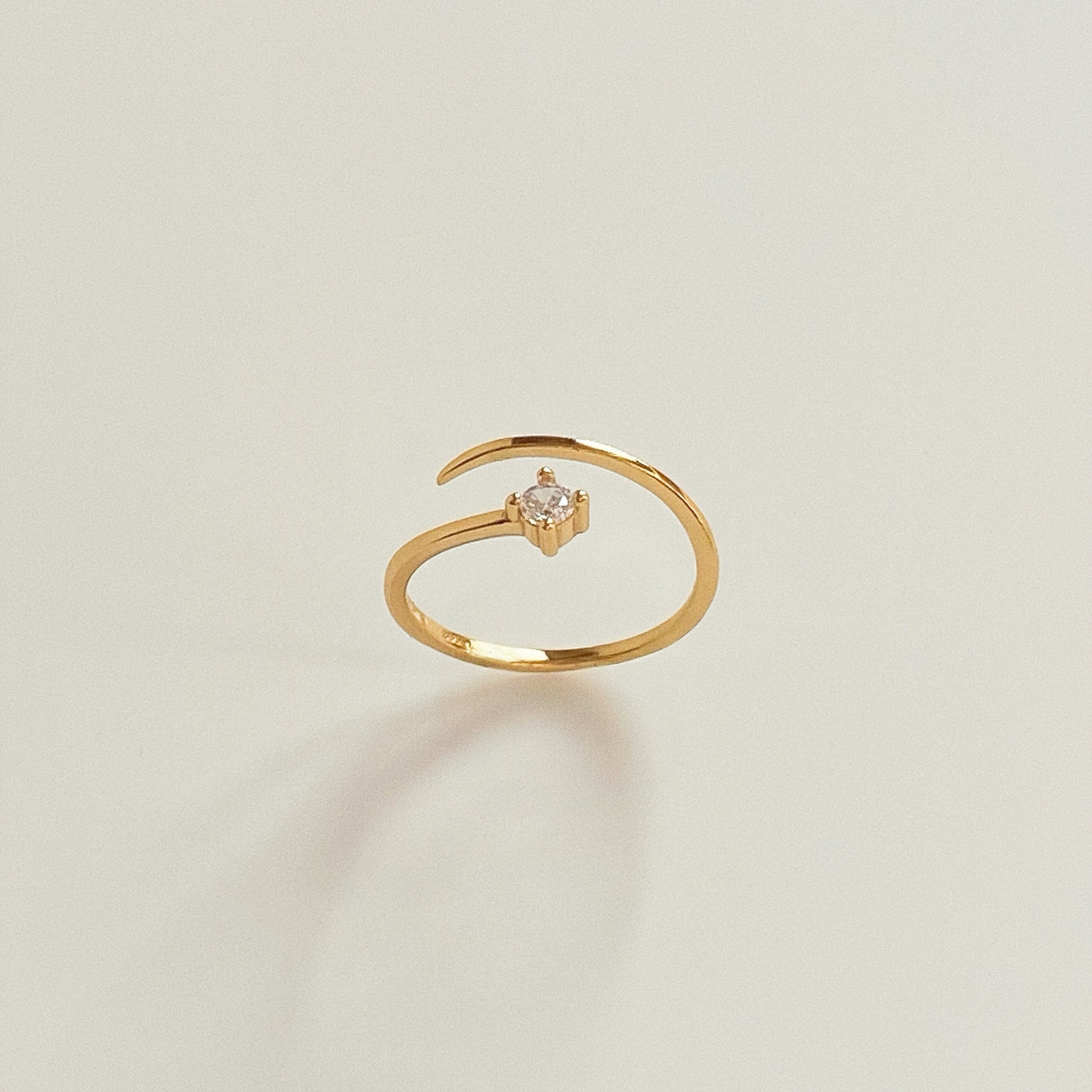 Solo Spark adjustable gold pinky ring standing upright with single cubic zirconia facing forward on light background