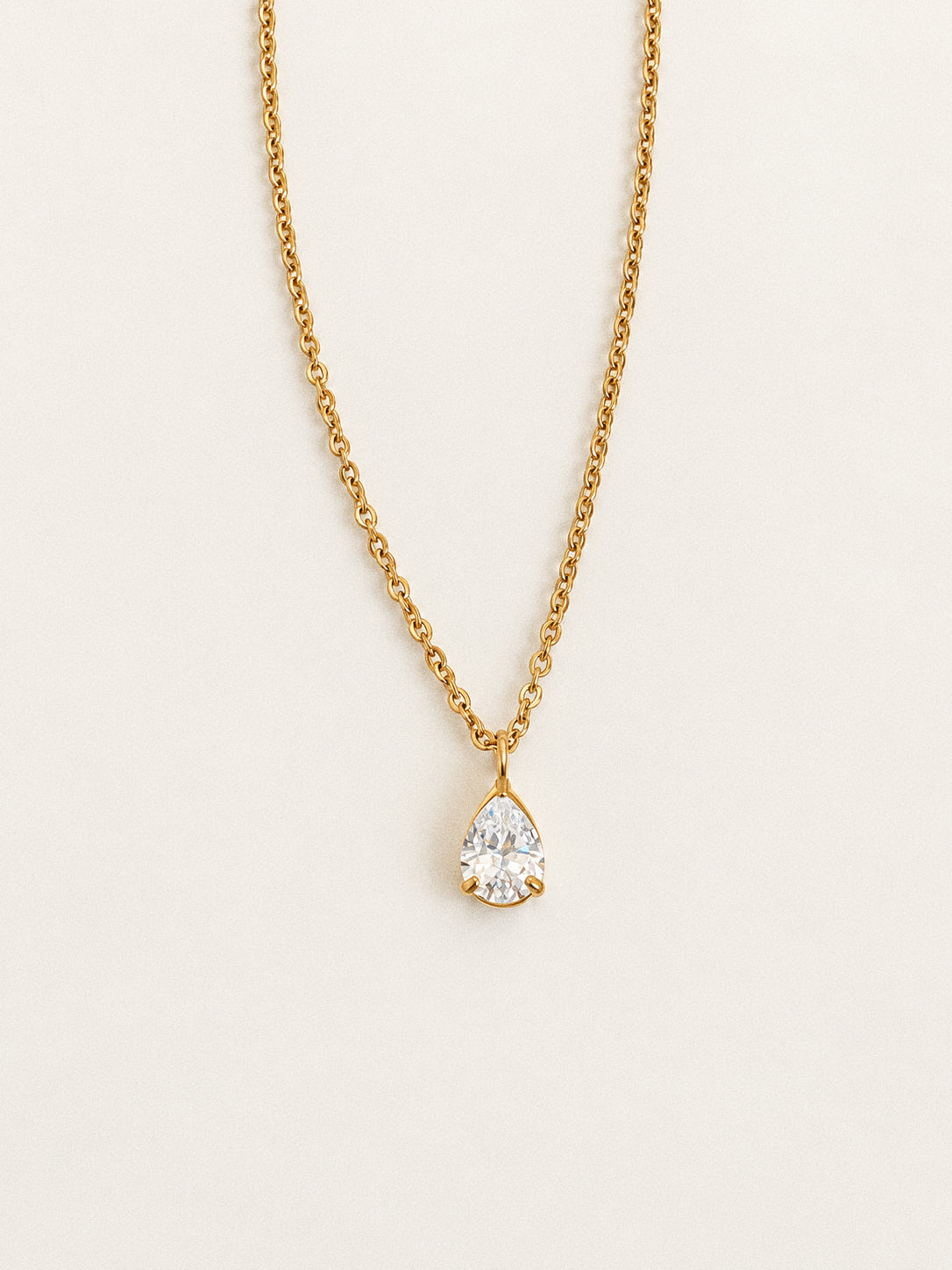 Front view of the Goutte gold-plated teardrop pendant necklace against an ivory background.