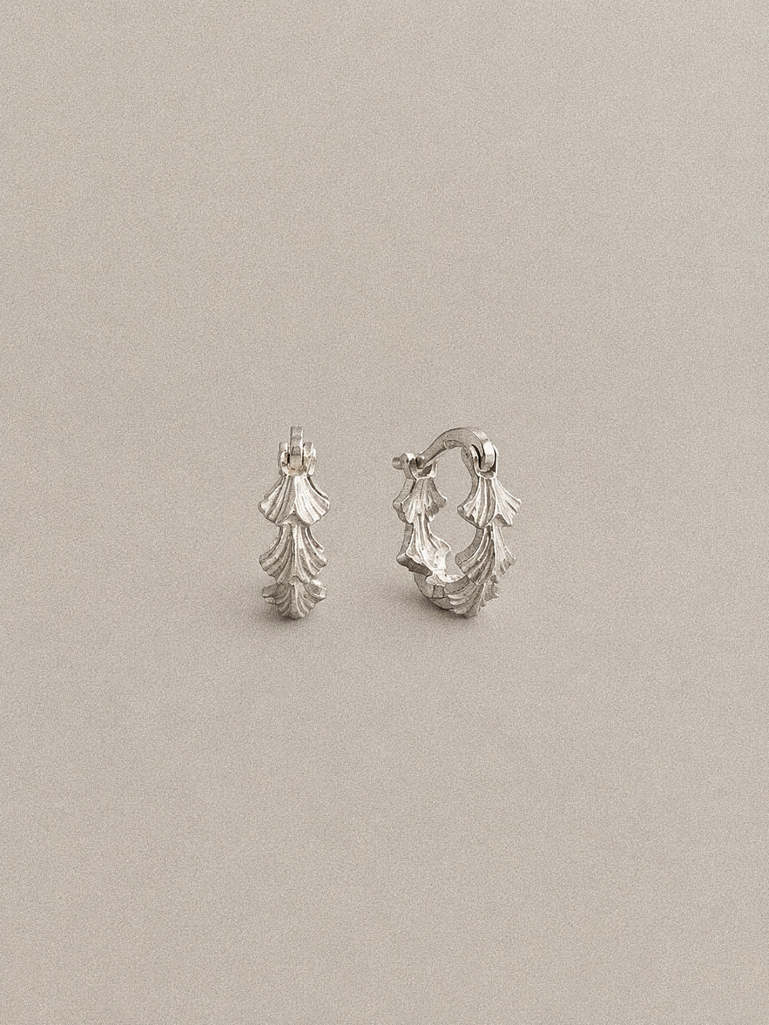 Grove sterling silver leaf hoop earrings with a sculpted fan-shaped leaf pattern around the small hoop.