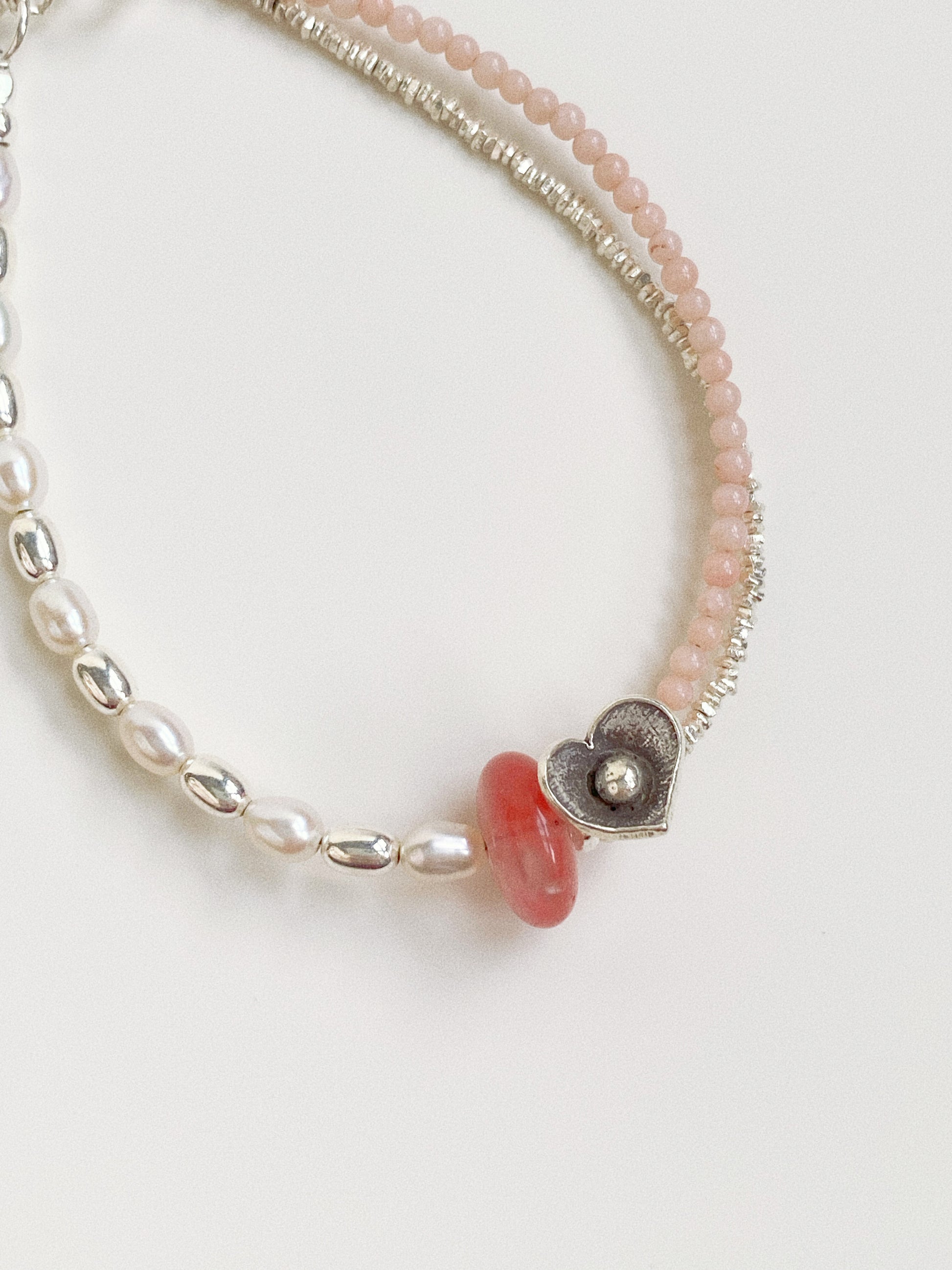 Close-up of unique hand-rubbed 990 fine silver grains and a Thai silver flower charm on a gemstone bracelet.