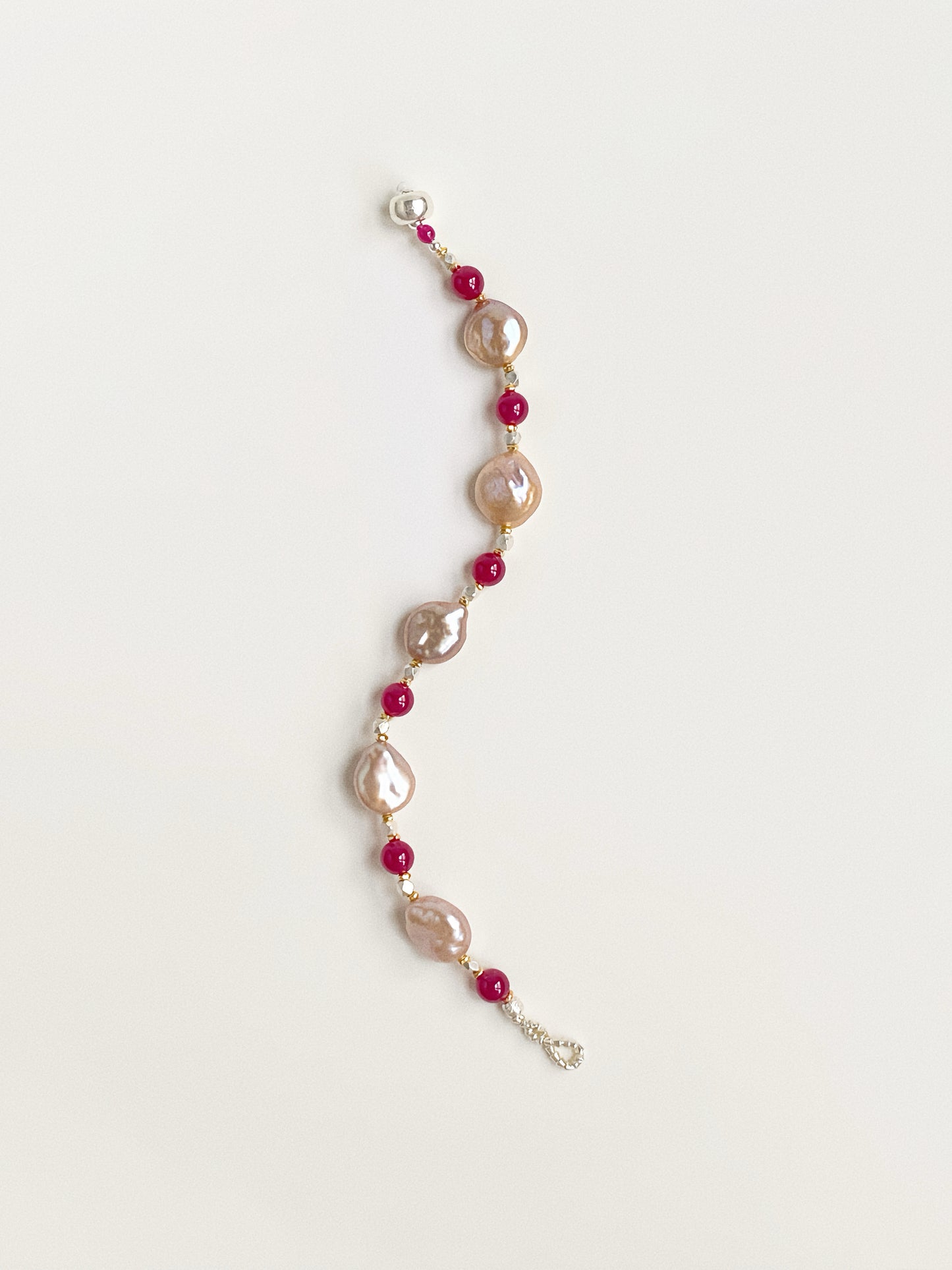 S-curve display of a 18cm handmade pearl and corundum strand showcasing organic shapes and 925 silver clasp.