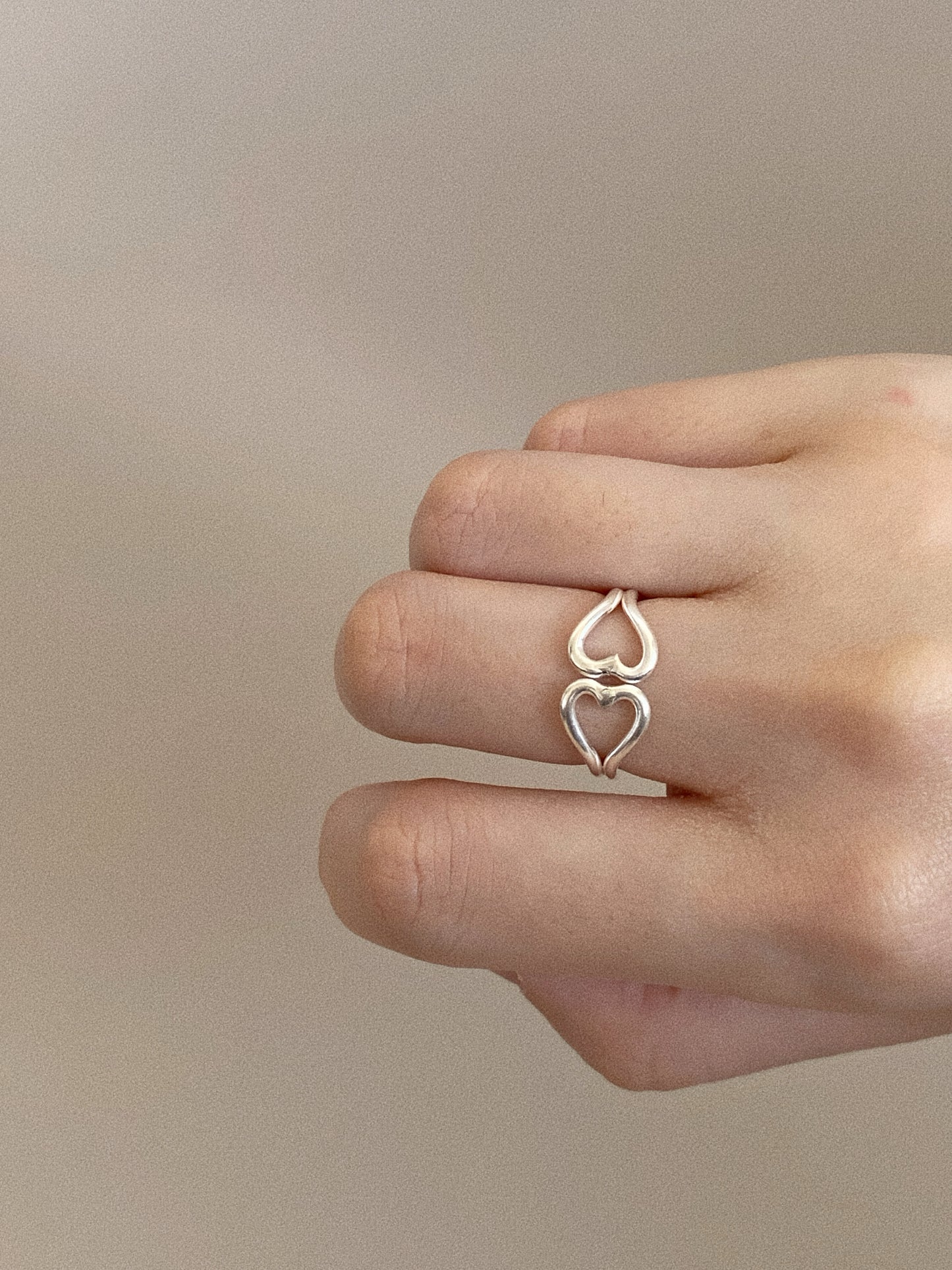 Echo double heart ring in handmade 925 sterling silver worn on the finger, open hearts stacked tip to tip.