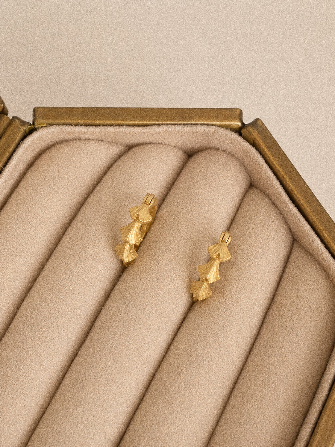 Close view of the Grove handmade gold leaf hoop earrings showing the cast texture and layered botanical form.