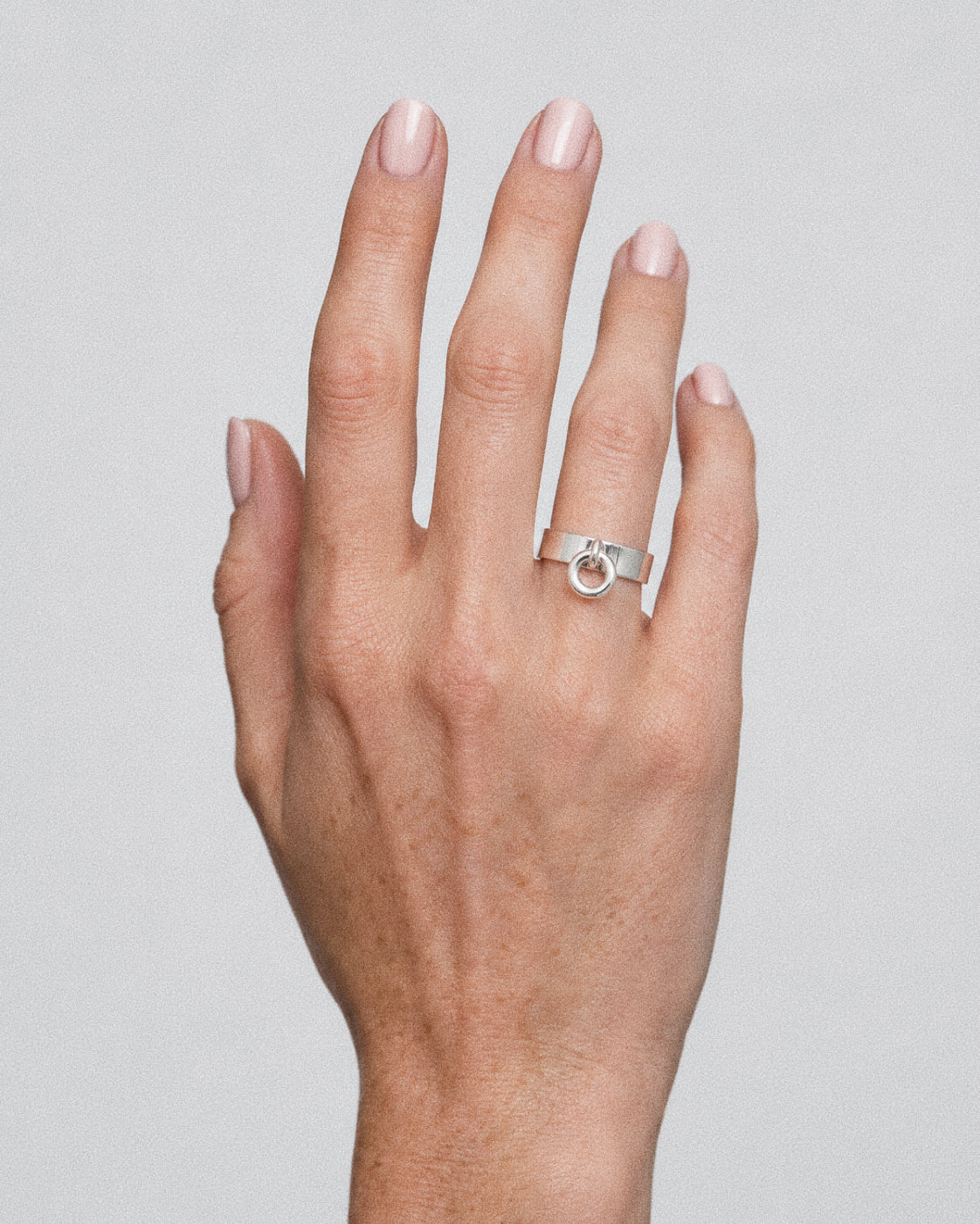 Orbit charm ring in handmade 925 sterling silver worn on the ring finger, a small hoop swinging from the wide band.