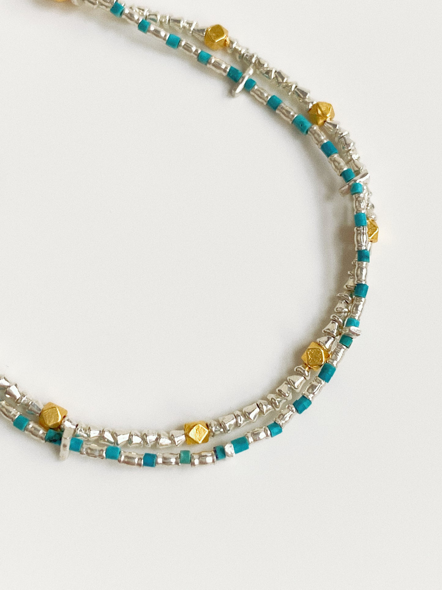 Macro view of handmade Thai silver and natural turquoise beaded bracelet showing artisan bead texture