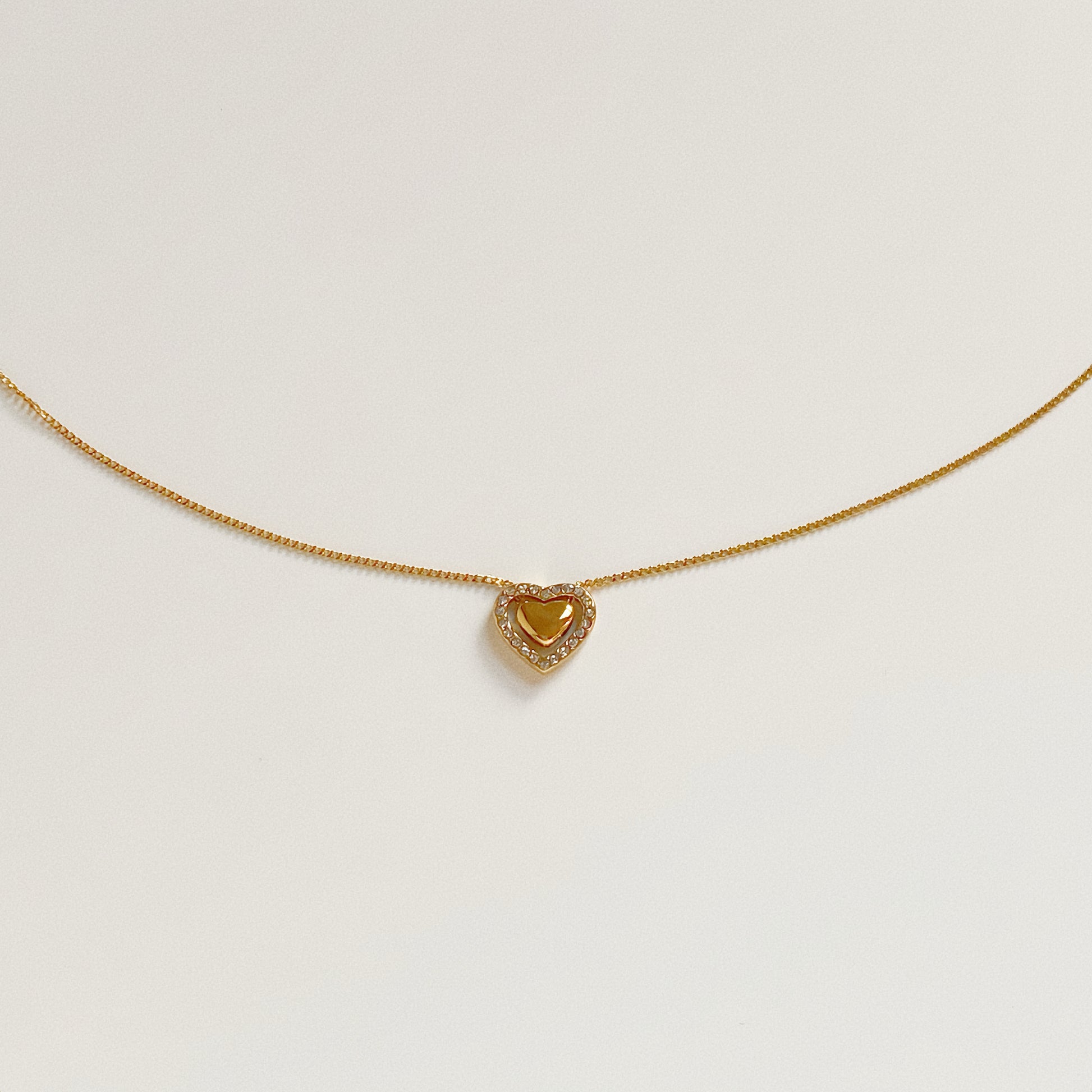 Isolated flat lay of the Fluttering Heart Necklace, a stainless steel waterproof pendant with cubic zirconia details.