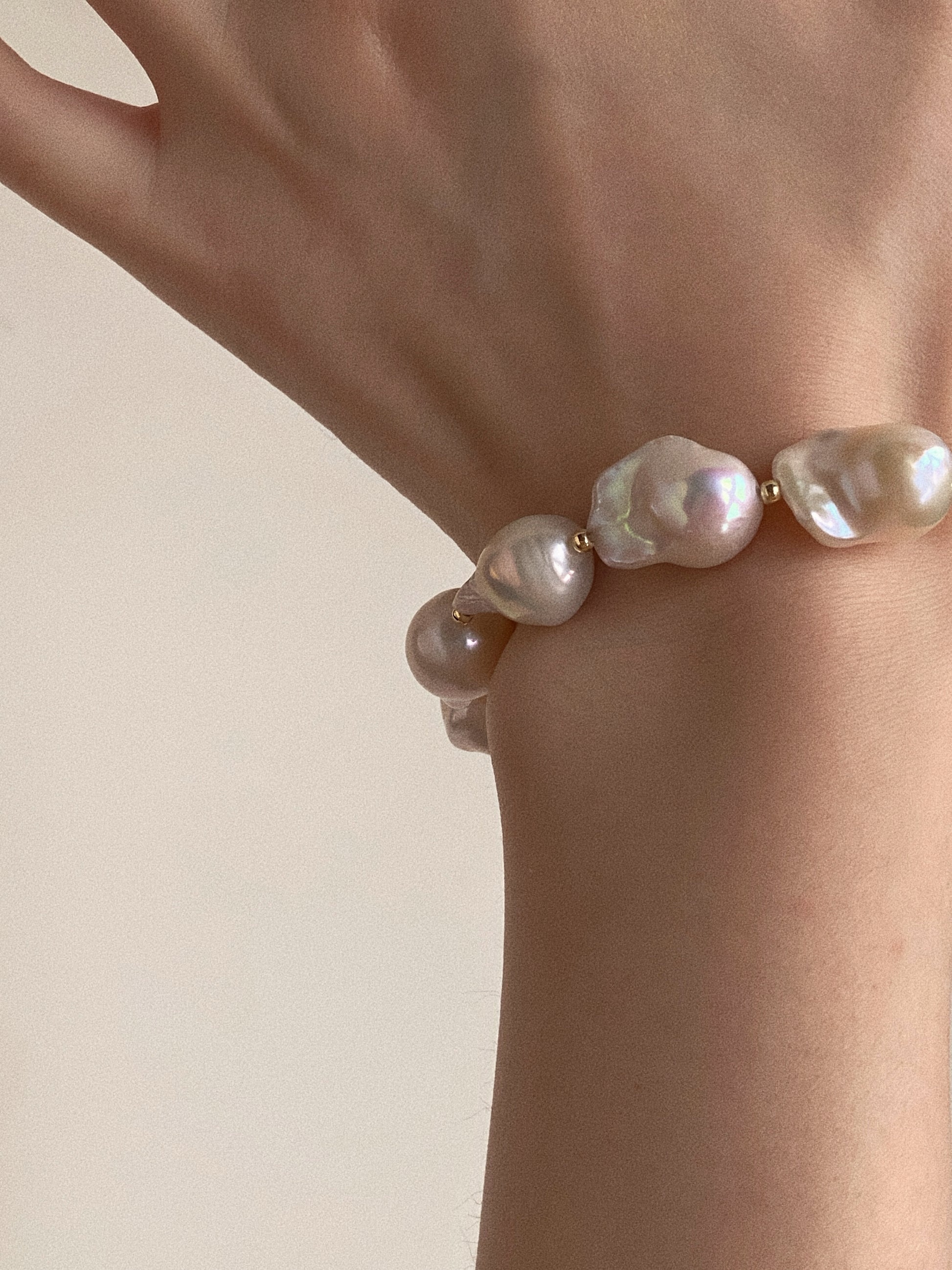 Close up on wrist showing the intense iridescent luster of the large fish-tail baroque pearls.
