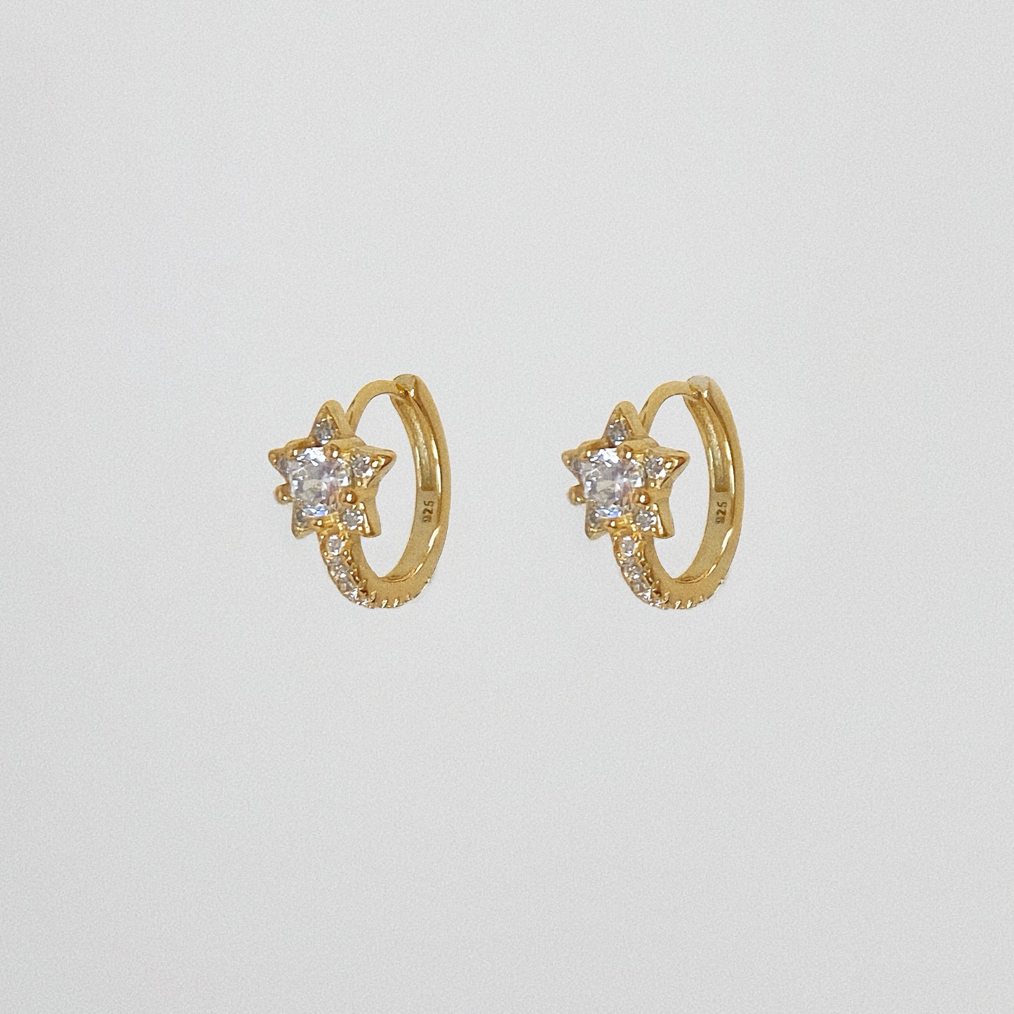 Close up of gold vermeil star hoop earrings featuring cubic zirconia stones, isolated on white background.
