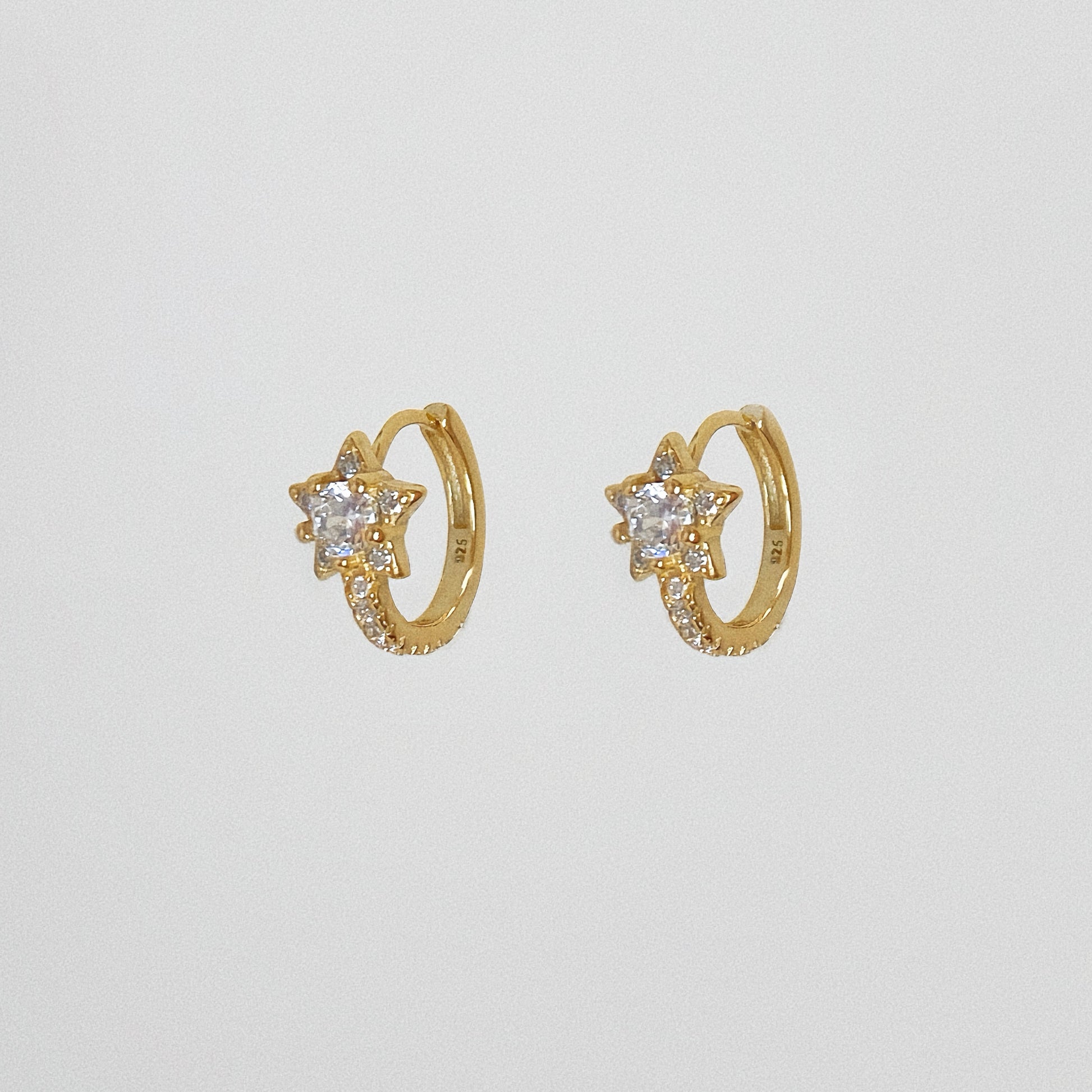 Close up of gold vermeil star hoop earrings featuring cubic zirconia stones, isolated on white background.