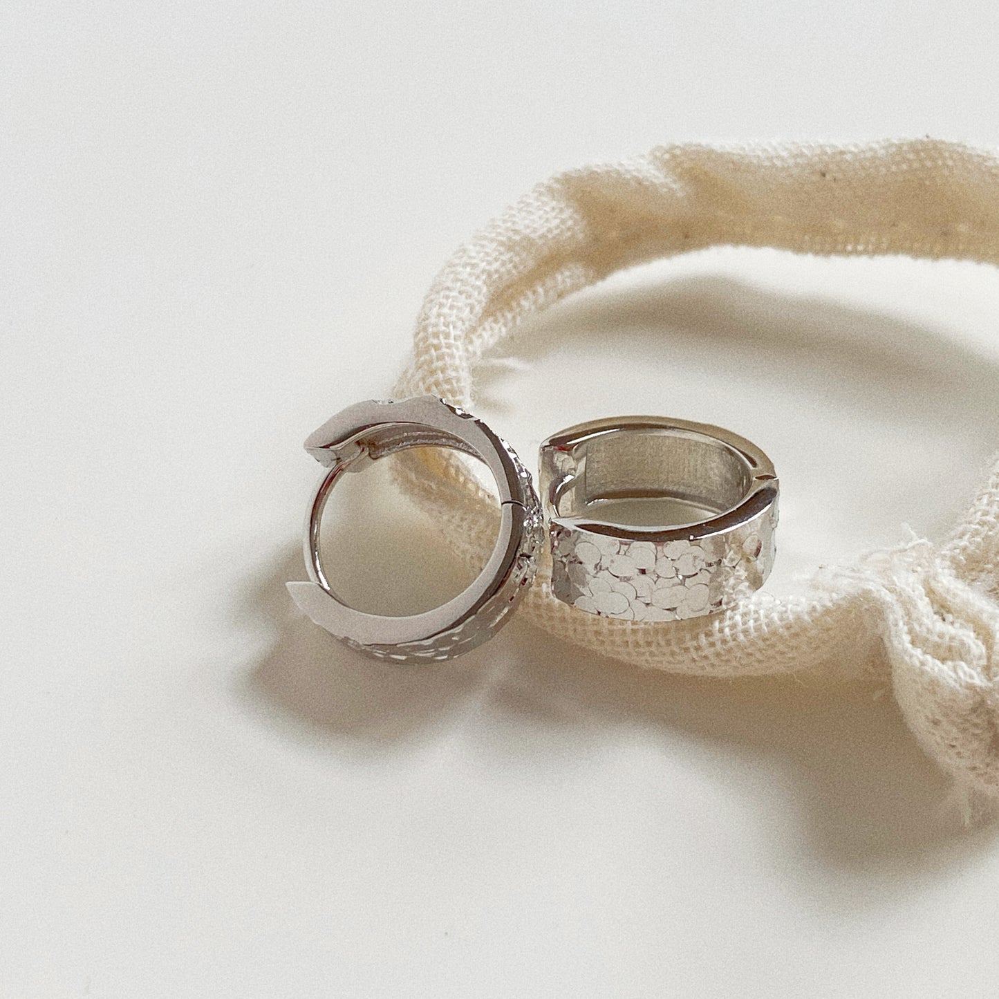 Pair of 925 Sterling Silver textured huggie earrings displayed on a Deja Vu canvas pouch.