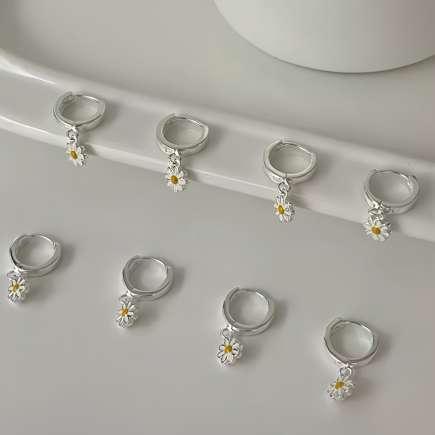 Close-up of multiple daisy charm huggie hoop earrings on display