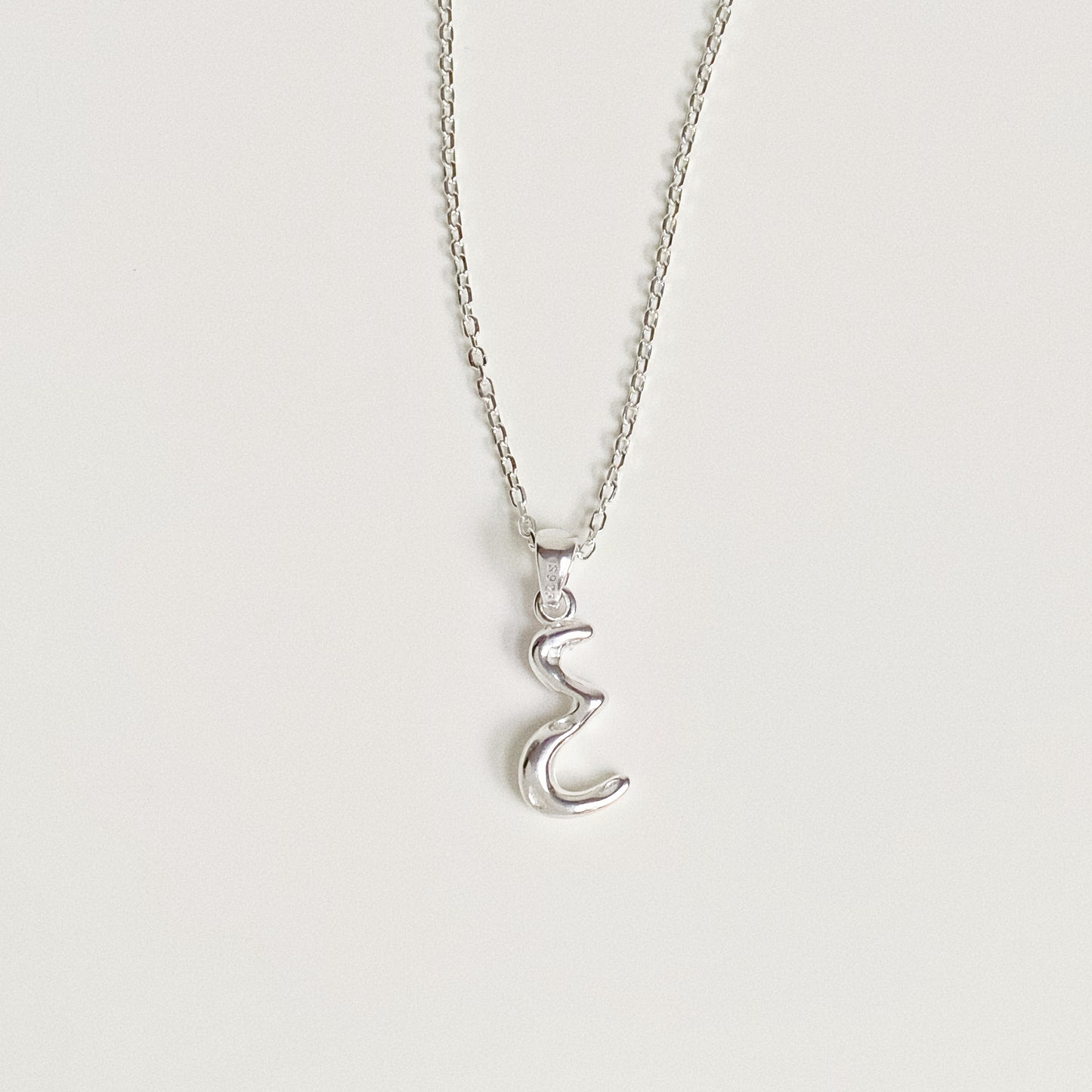 Silver initial necklace with organic bubble font pendant showing connection to the chain.