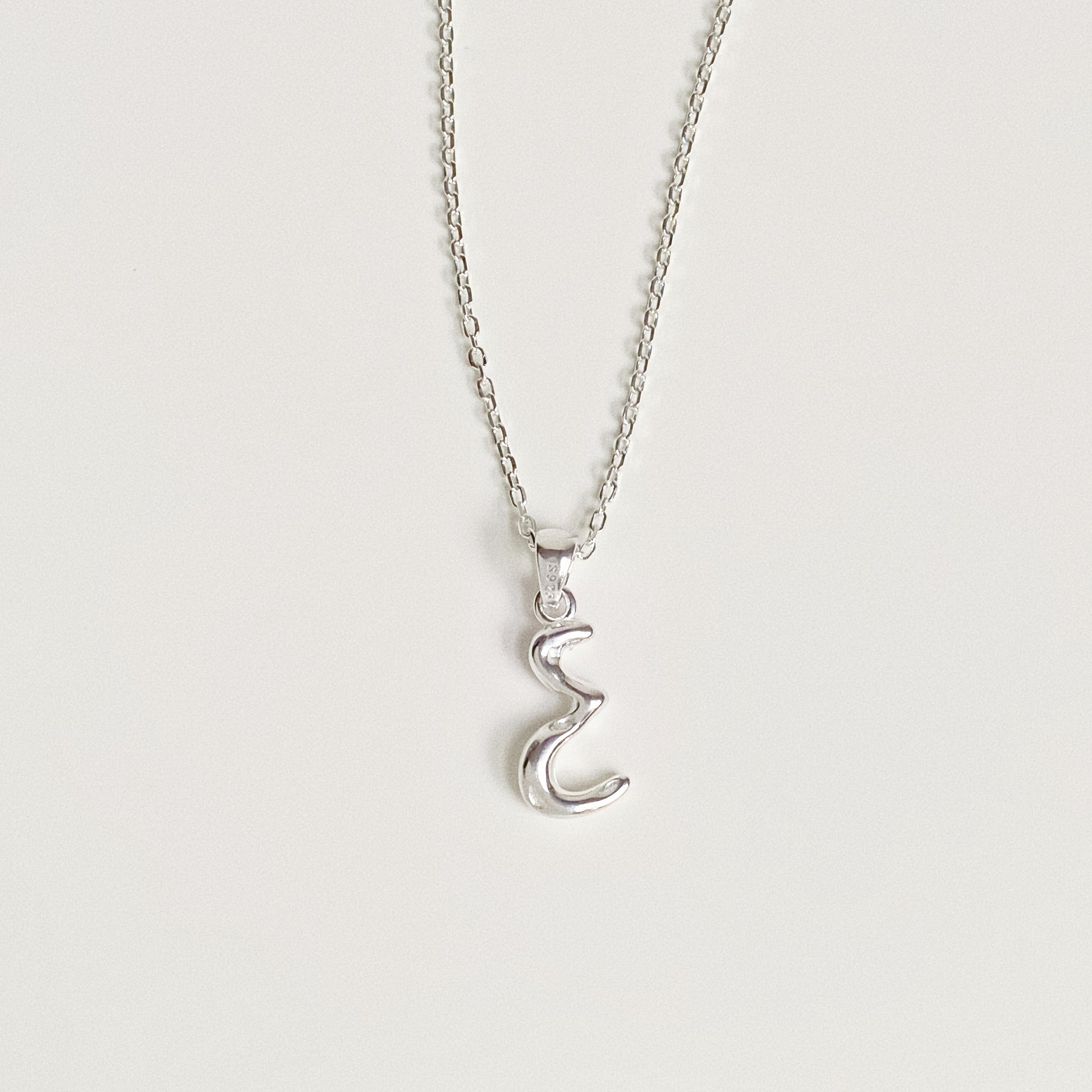 Silver initial necklace with organic bubble font pendant showing connection to the chain.