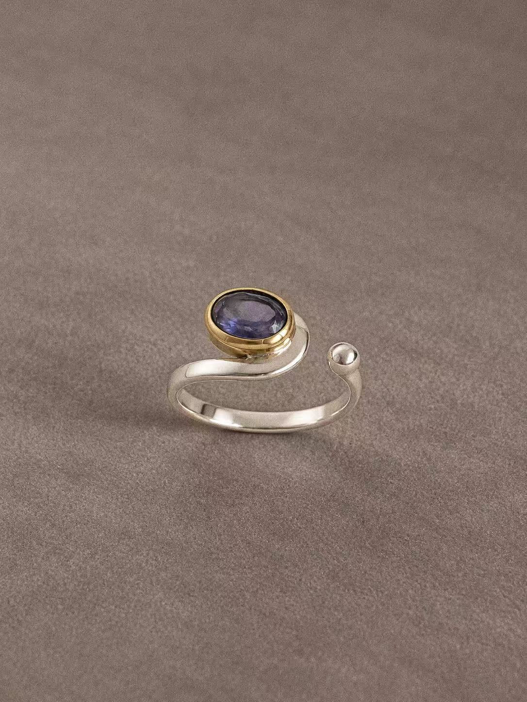 Front view of the iolite ring with its brass bezel, curved silver band and rounded open end