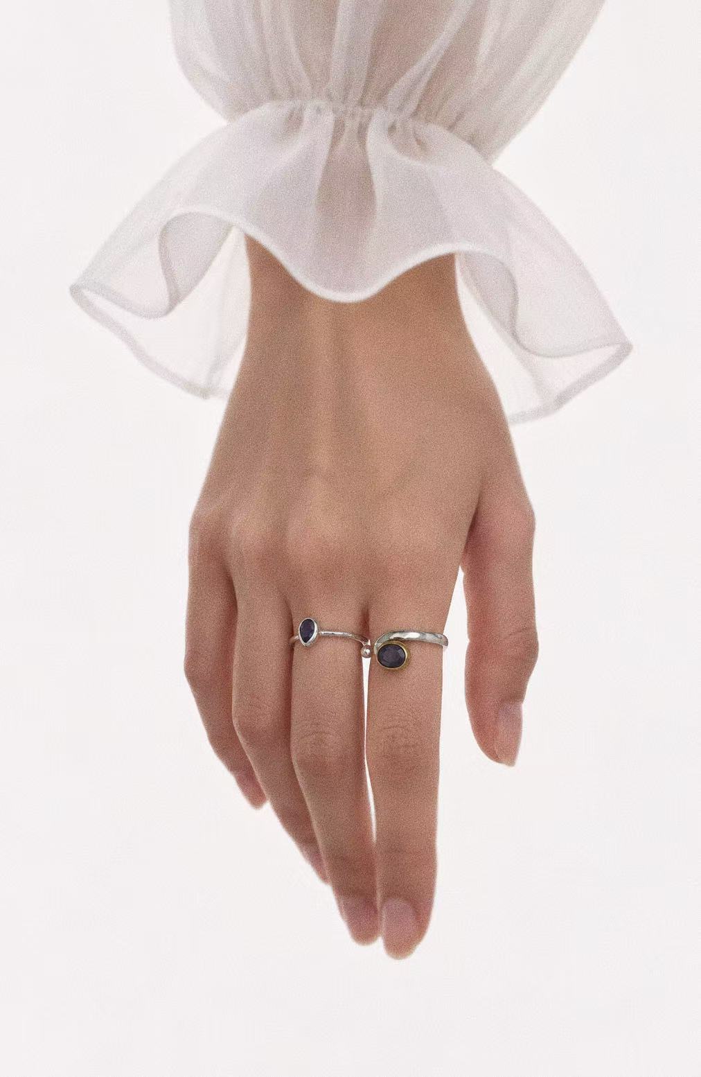 Iolite teardrop ring worn beside a larger gemstone ring with a white blouse; jewellery styling image