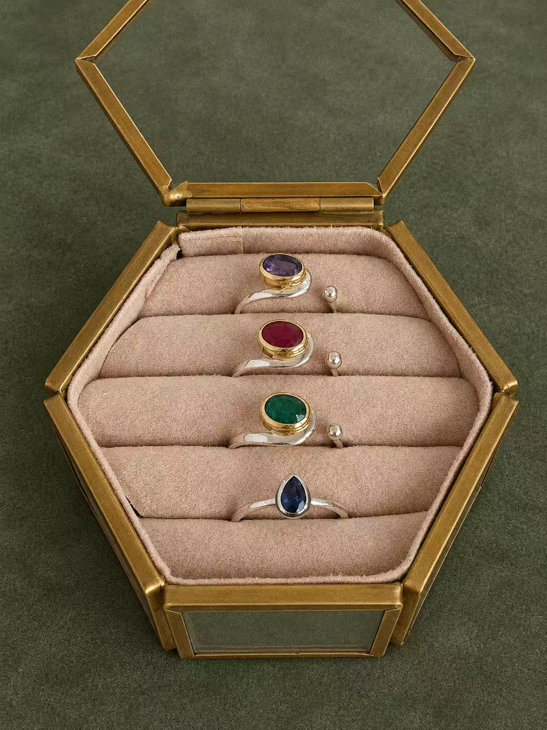 Iolite two-tone open ring at the top of a jewellery box with other gemstone rings; styling image