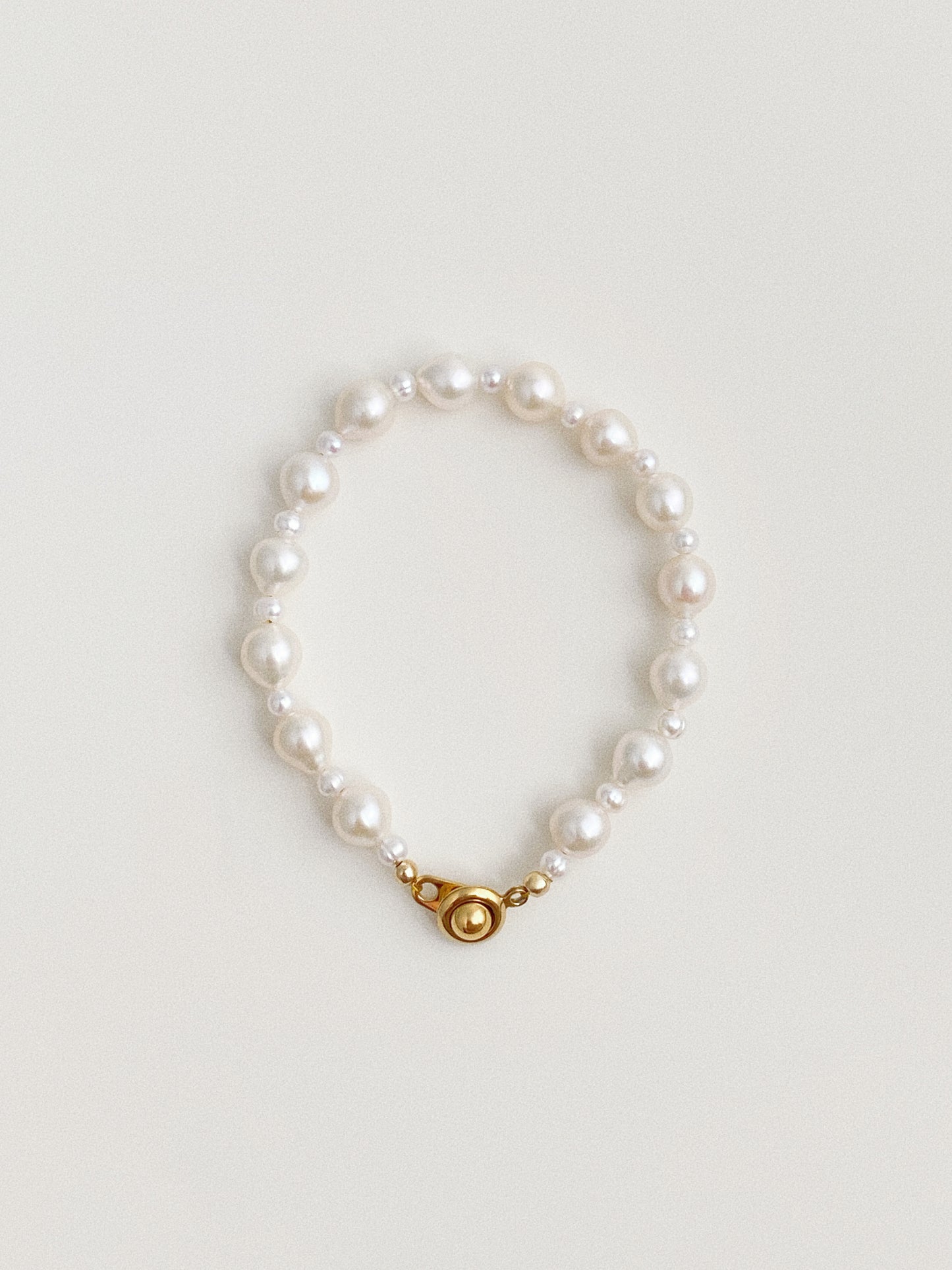 Keshi baroque freshwater pearl bracelet with round gold-plated clasp on neutral background