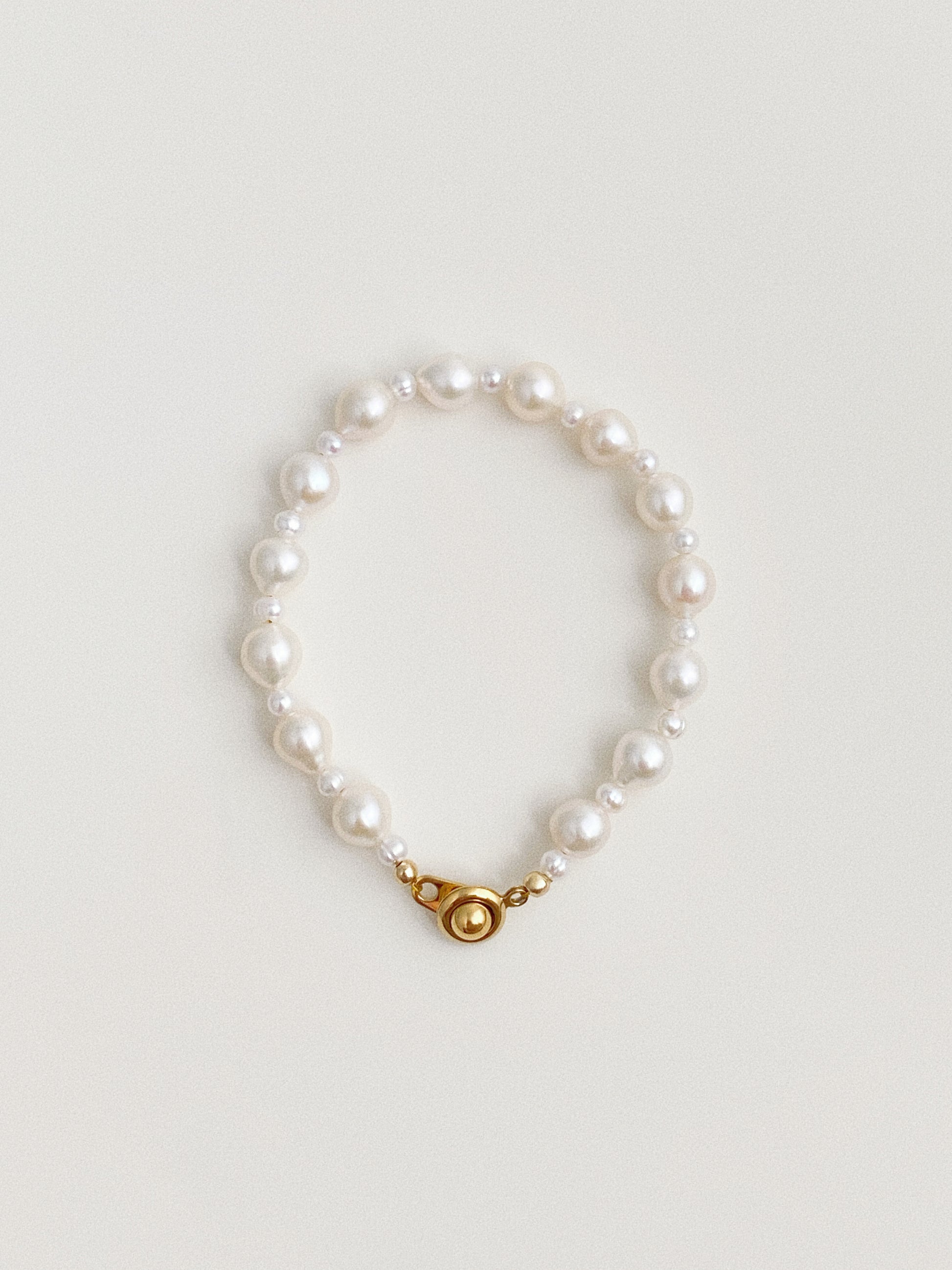 Keshi baroque freshwater pearl bracelet with round gold-plated clasp on neutral background