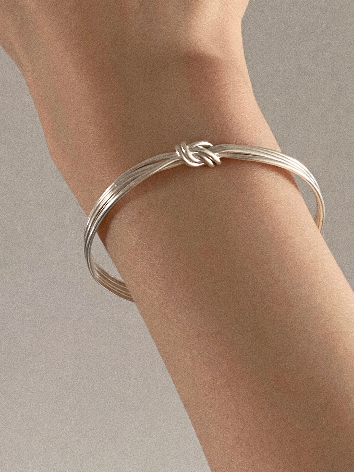 Close view of the Knot multi strand silver bangle worn alone with the knot at the top of the wrist