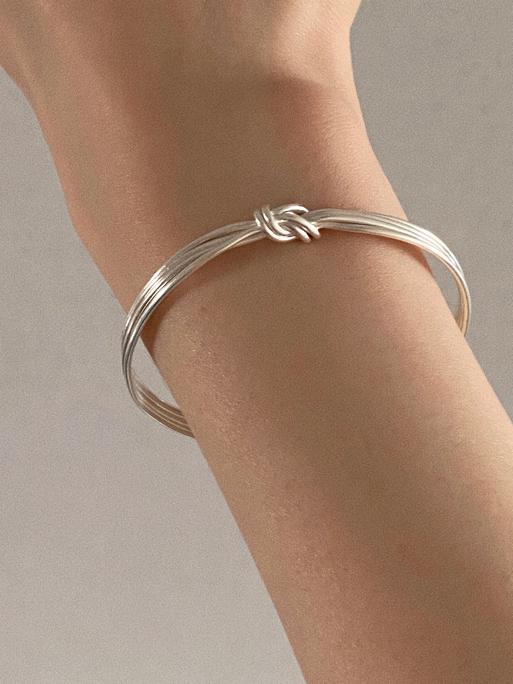 Close view of the Knot multi strand silver bangle worn alone with the knot at the top of the wrist