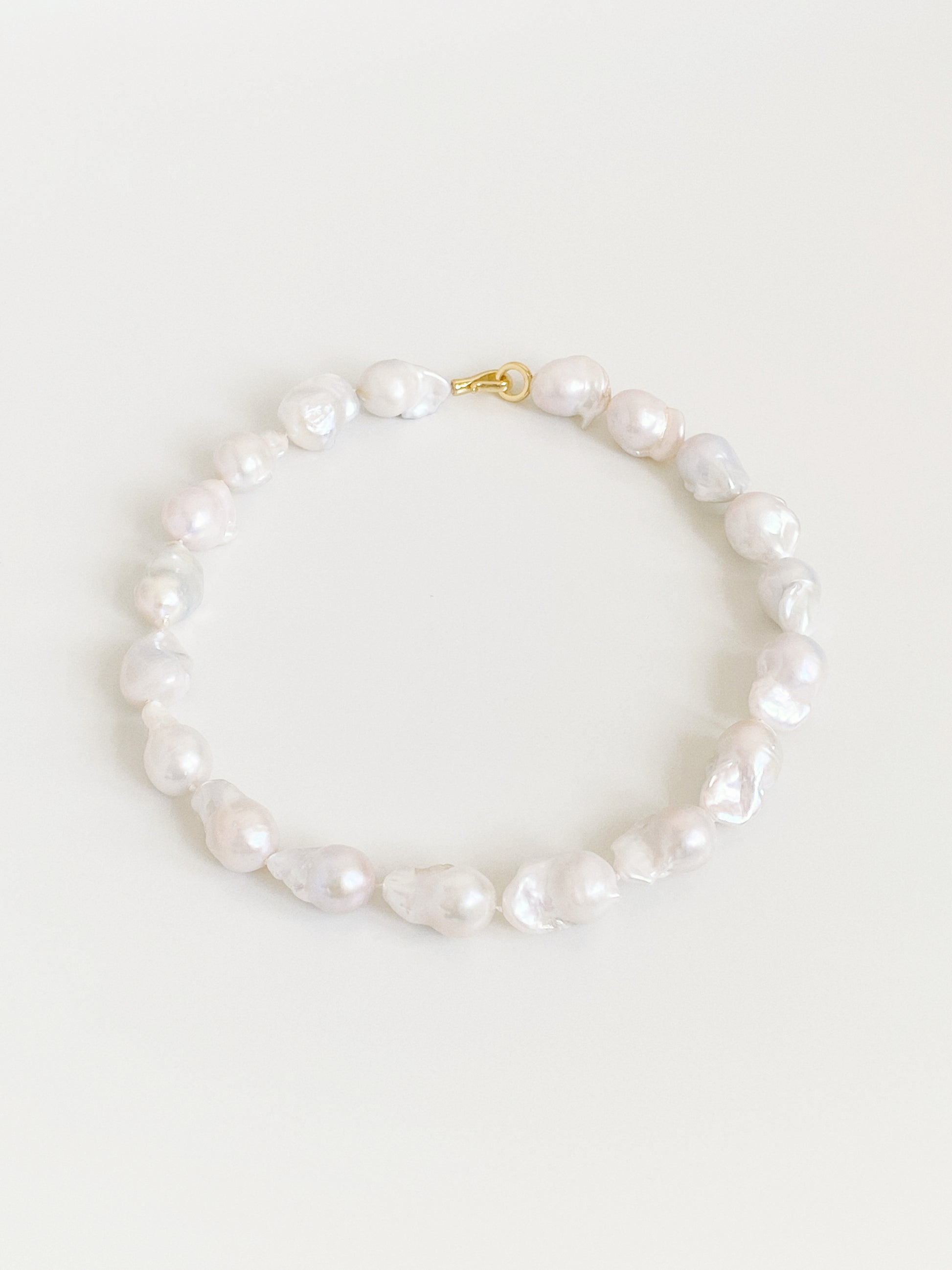 Angled flat lay of an 11-12mm natural baroque pearl necklace showing the individually shaped pearls and their soft iridescent lustre