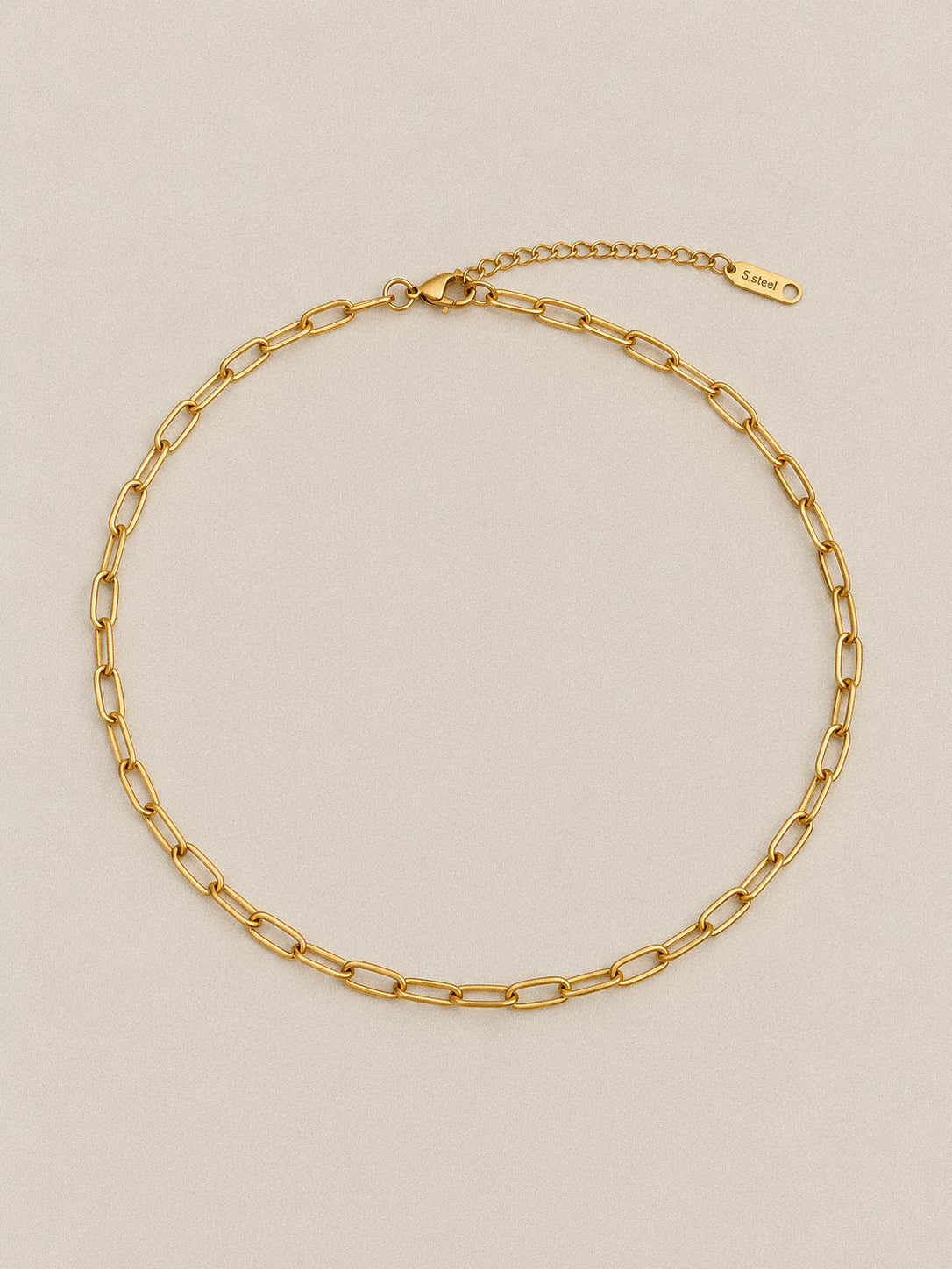Linea paperclip chain necklace laid in an oval, with the lobster clasp and extension chain visible at the top.