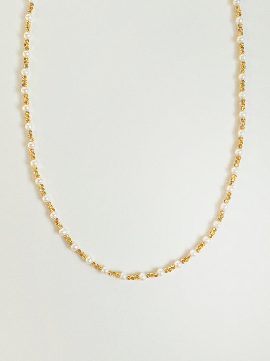 Long pearl and diamond-cut gold bead necklace by Deja Vu Jewellery shown vertically on neutral background