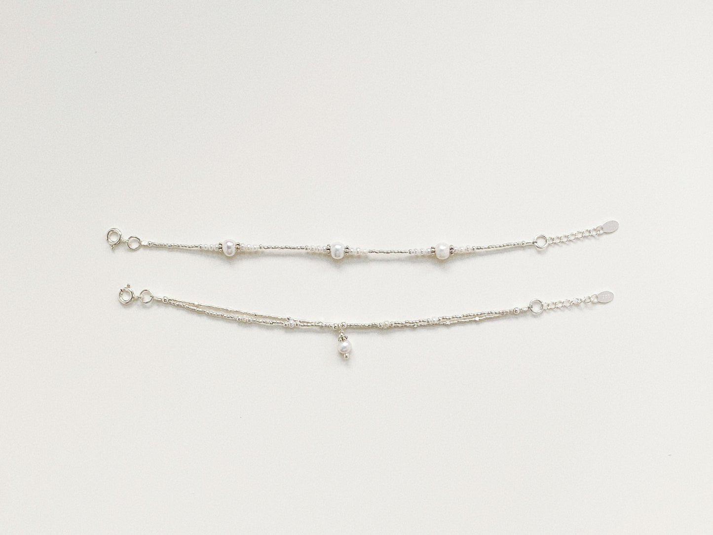 Comparison view of two delicate silver and pearl bracelets, showing the unique structured design.