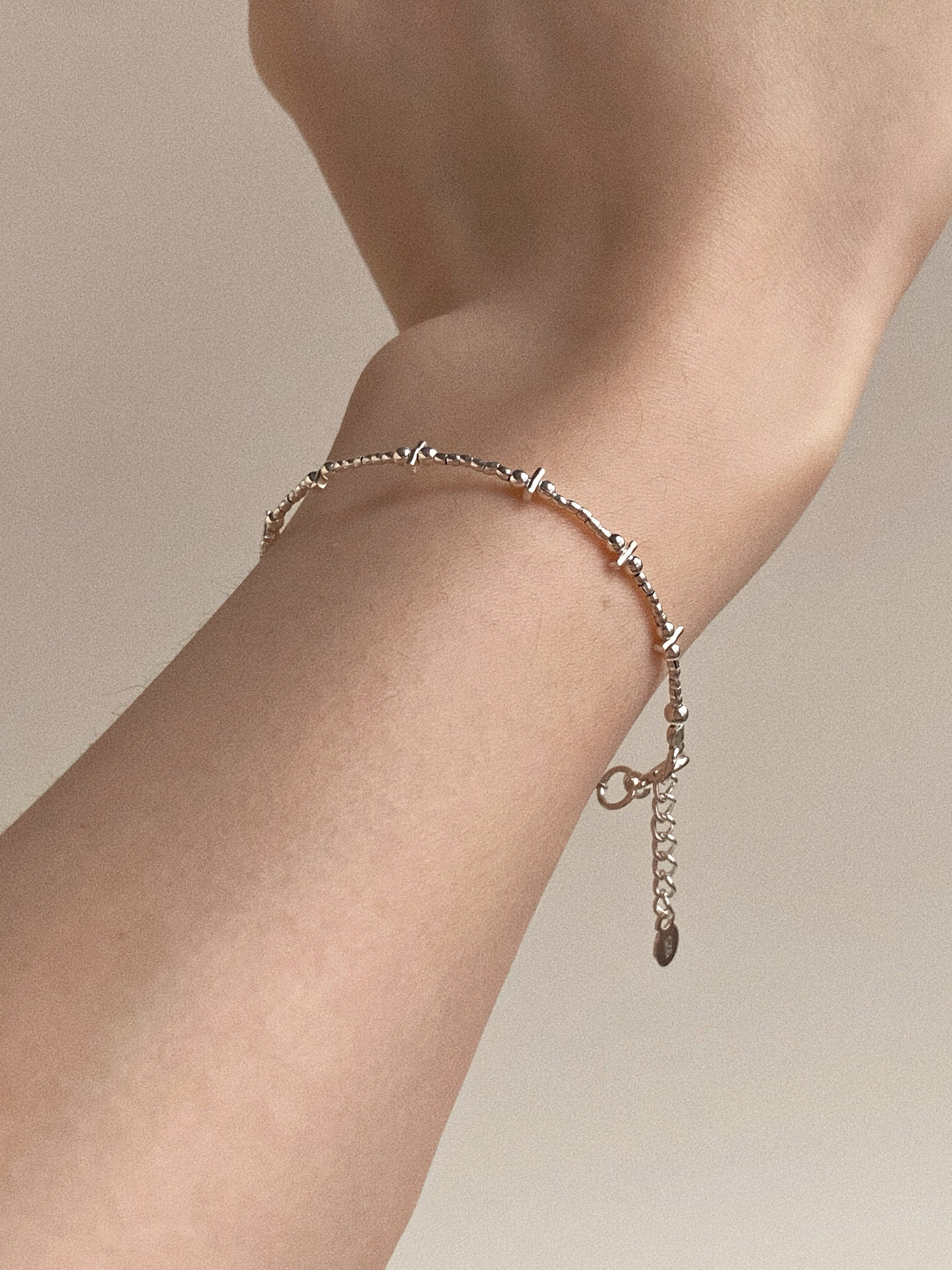 Model wearing The Essential Bar & Bead Silver Bracelet solo, showing the dainty fit and structural shape on the wrist.