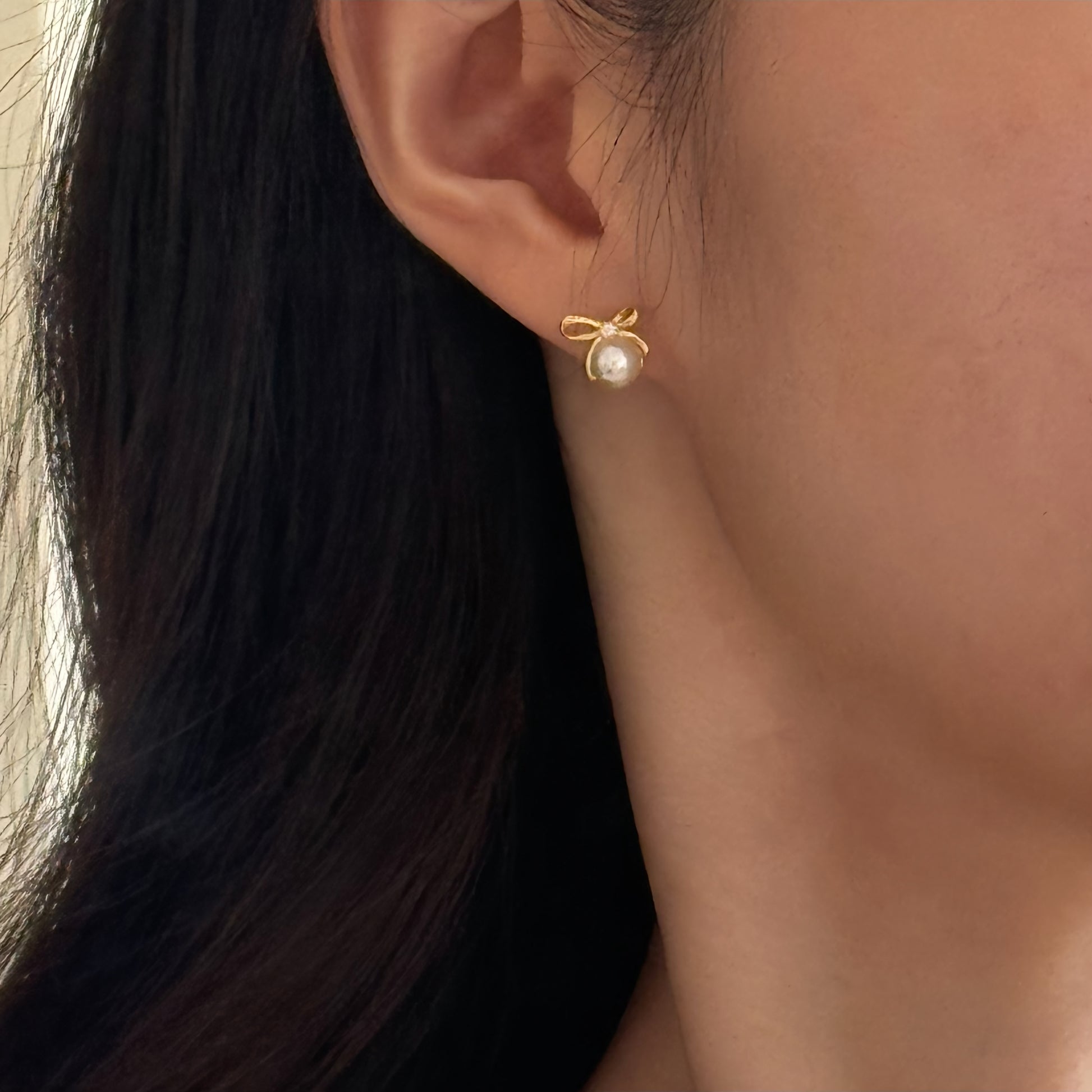 Gold bow ribbon pearl studs with tiny accent stone at knot, hypoallergenic posts