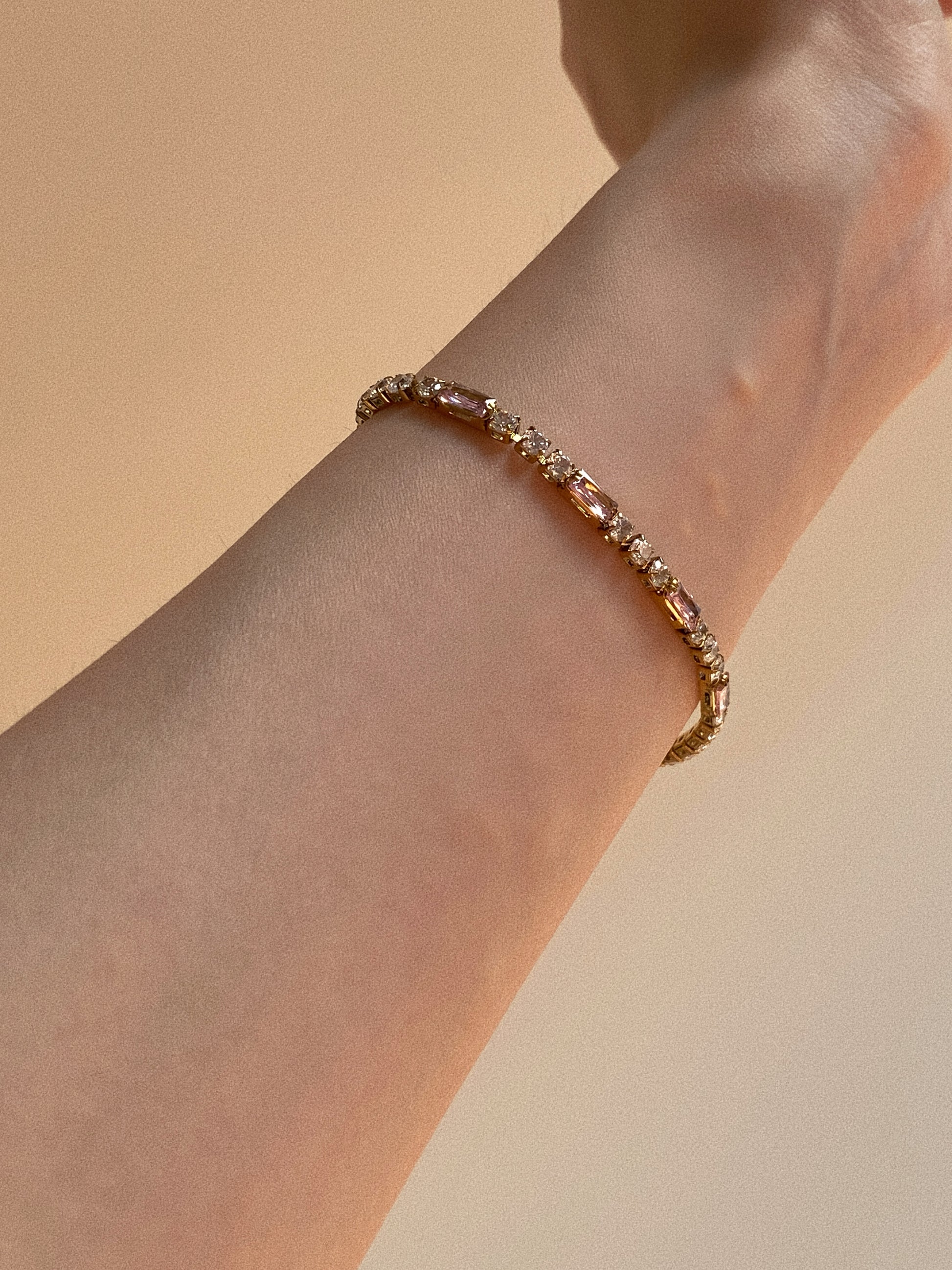 Close up of mixed cut tennis bracelet with pink rectangular stones, hypoallergenic stainless steel jewellery.