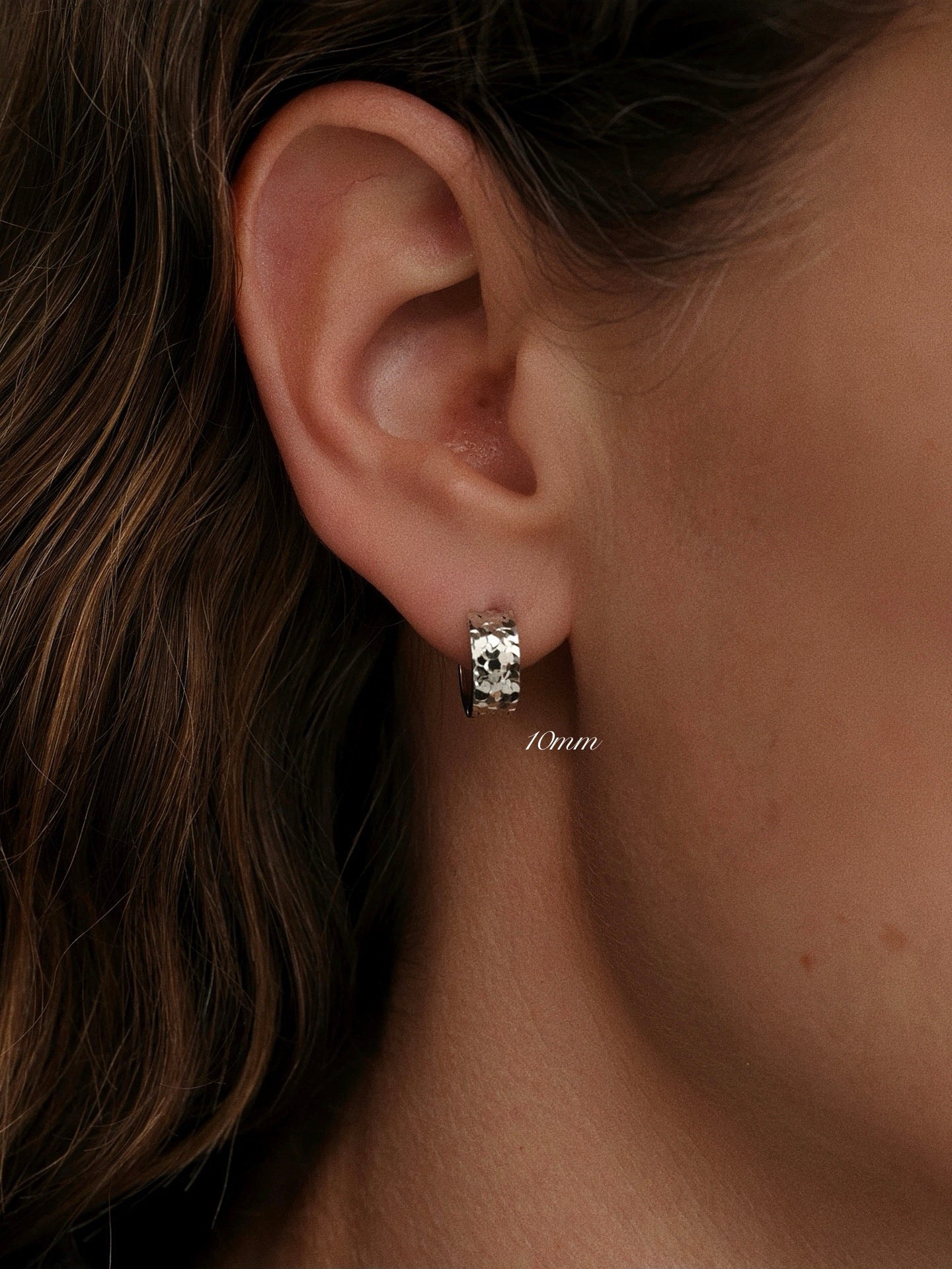 Model wearing 10mm textured silver hoop earring in first lobe piercing, showing standard fit.