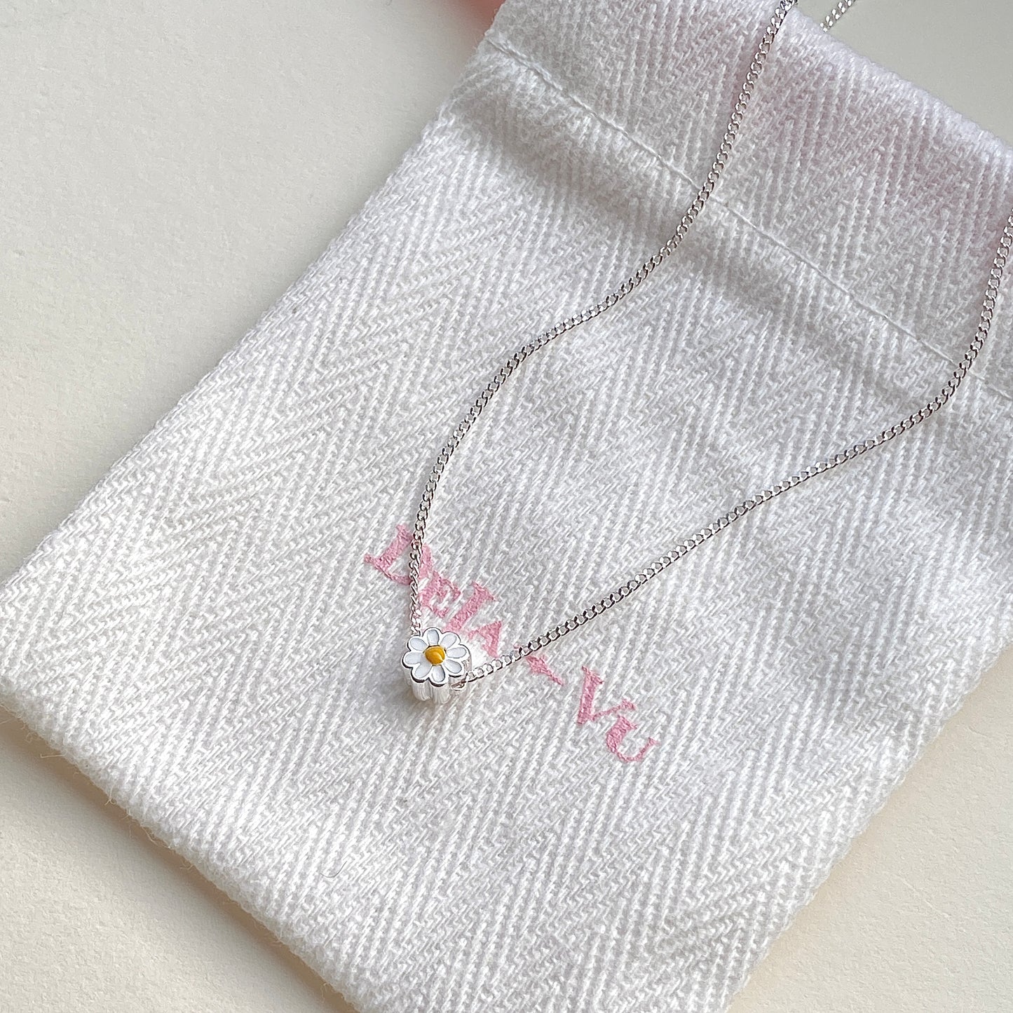 Daisy enamel necklace displayed with Deja vu jewellery pouch