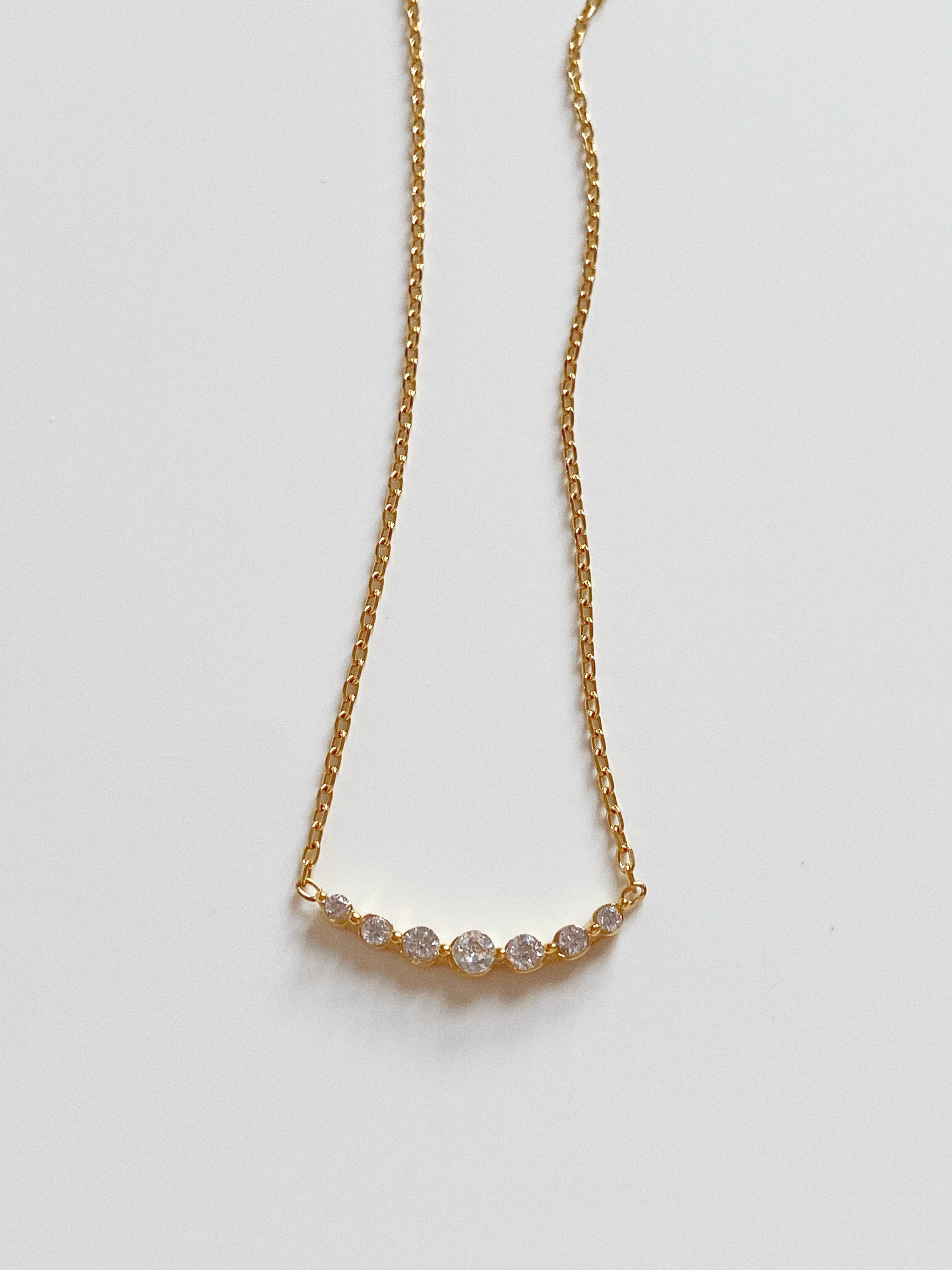 Minimalist gold necklace with a smiley face curve crystal pendant, waterproof jewellery flat lay.