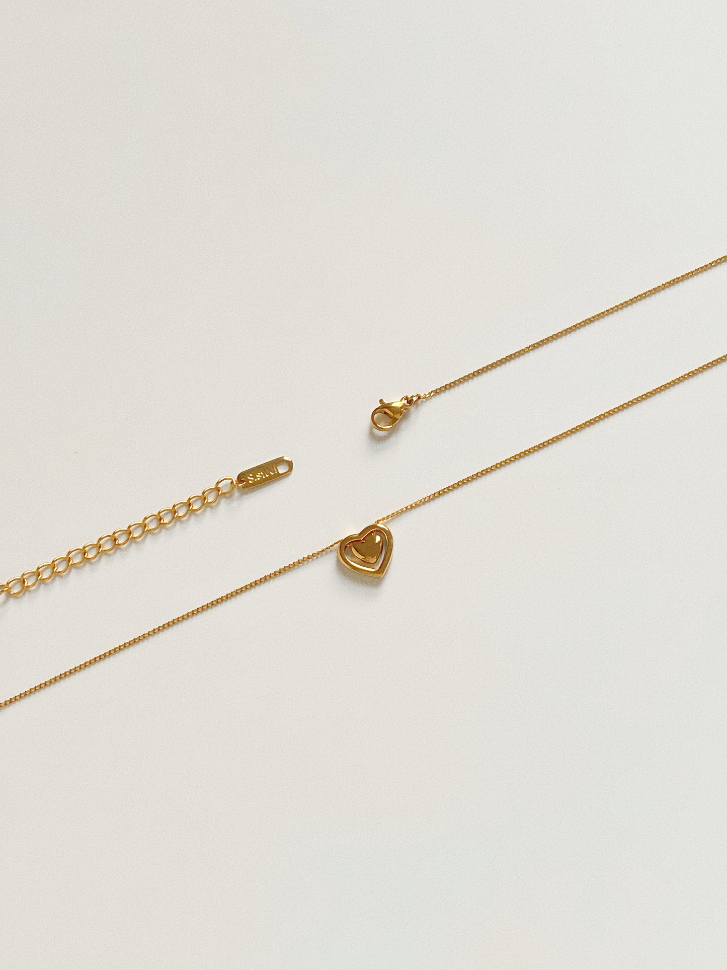 Detail of the adjustable extender chain and clasp on the gold heart necklace, ensuring a perfect fit.