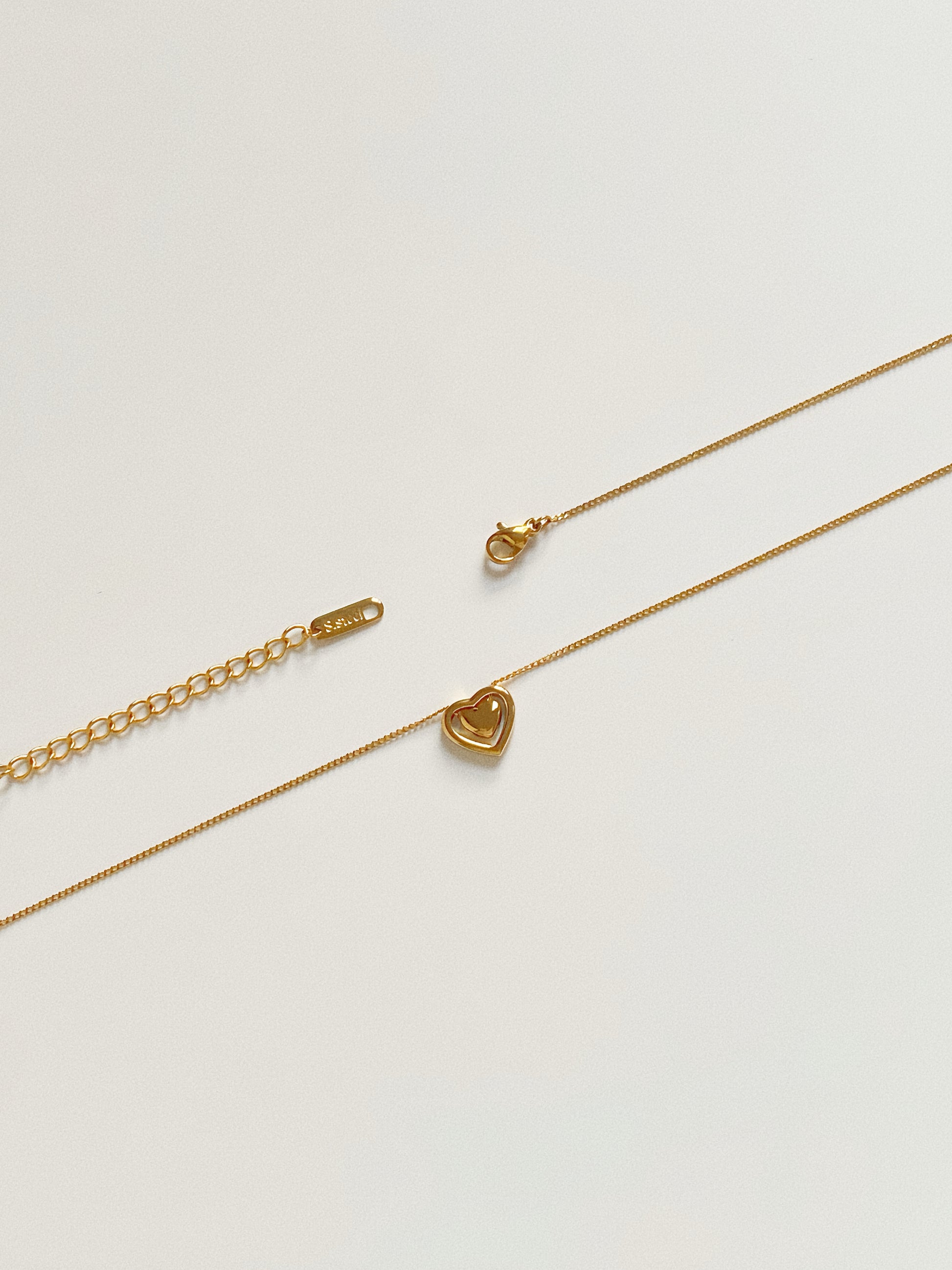 Detail of the adjustable extender chain and clasp on the gold heart necklace, ensuring a perfect fit.